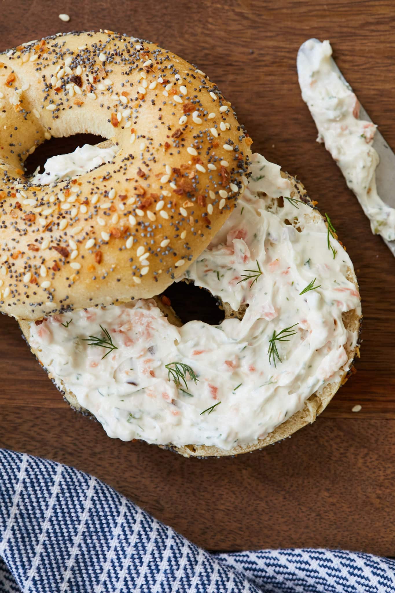 Homemade Smoked Salmon Cream Cheese with fresh dill is spread on an everything bagel.