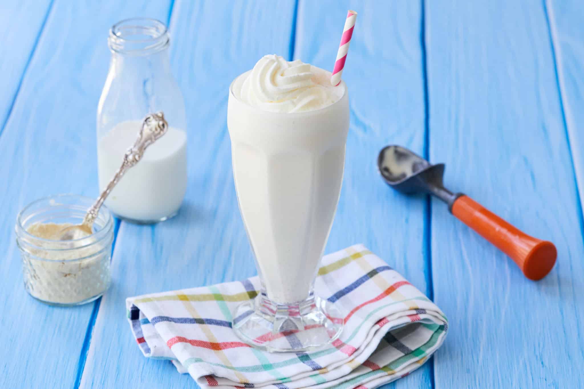 A vanilla malt milkshake next to ingredients and a scoop