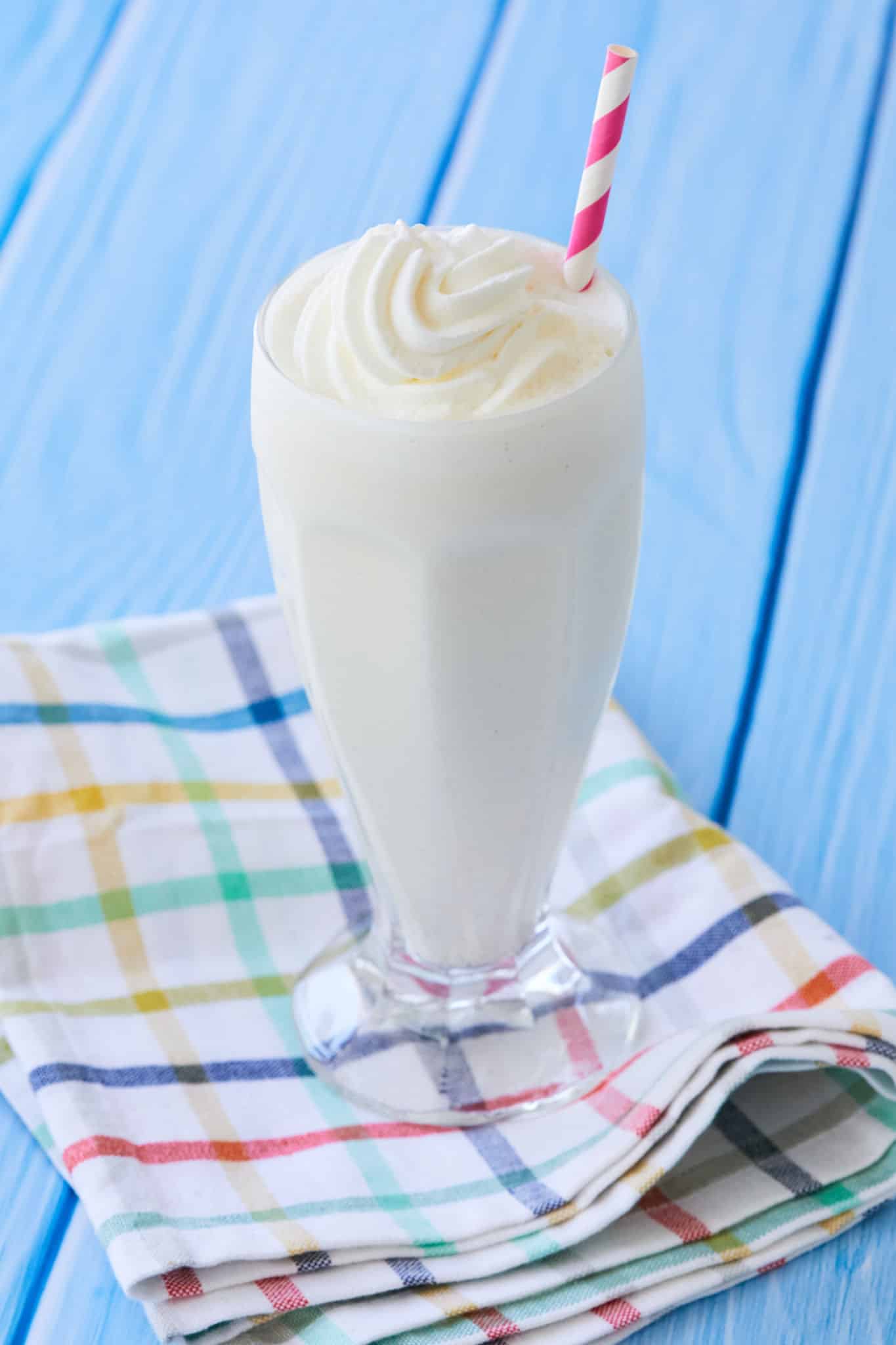 A finished vanilla malt milkshake topped with whipped cream