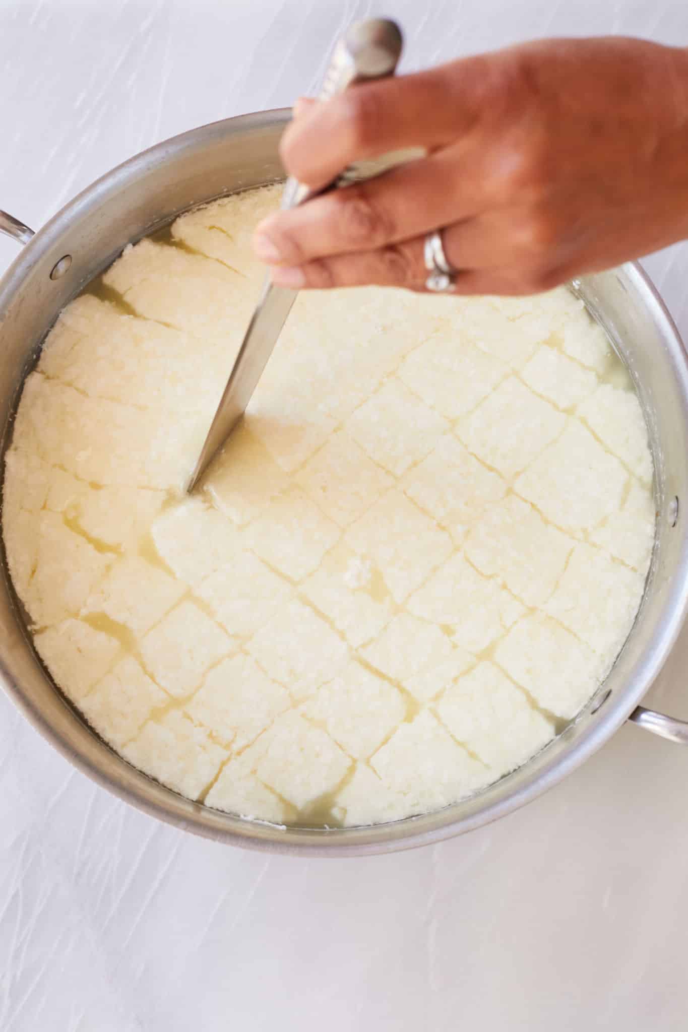 Step-by-step instructions on How to Make Homemade Mozzarella Cheese: Using a large knife, cut the curd all the way to the bottom of the pot in roughly 1-inch (2½-cm) strips. Then cut in the opposite direction to make a grid pattern.