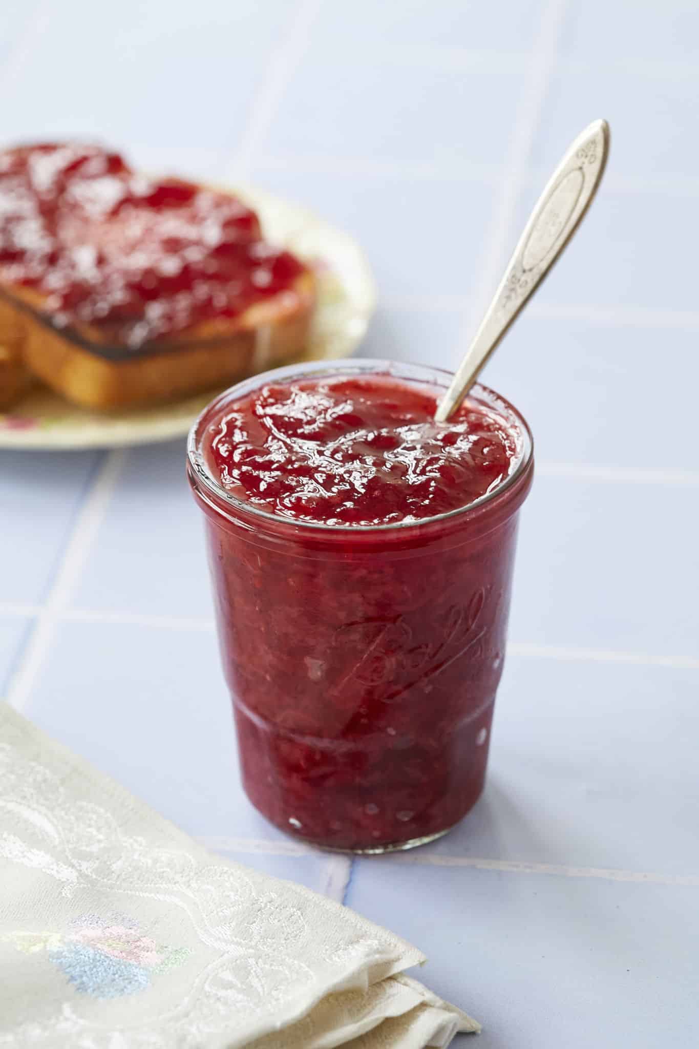 A spoon is dug into a jar of homemade jam.