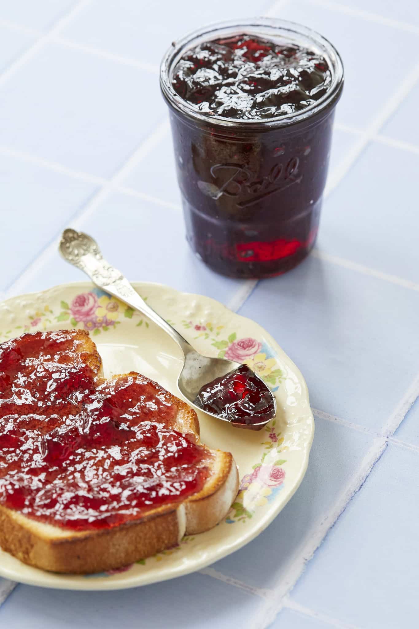 A jar of homemade jelly is displayed next to a slice of toast.