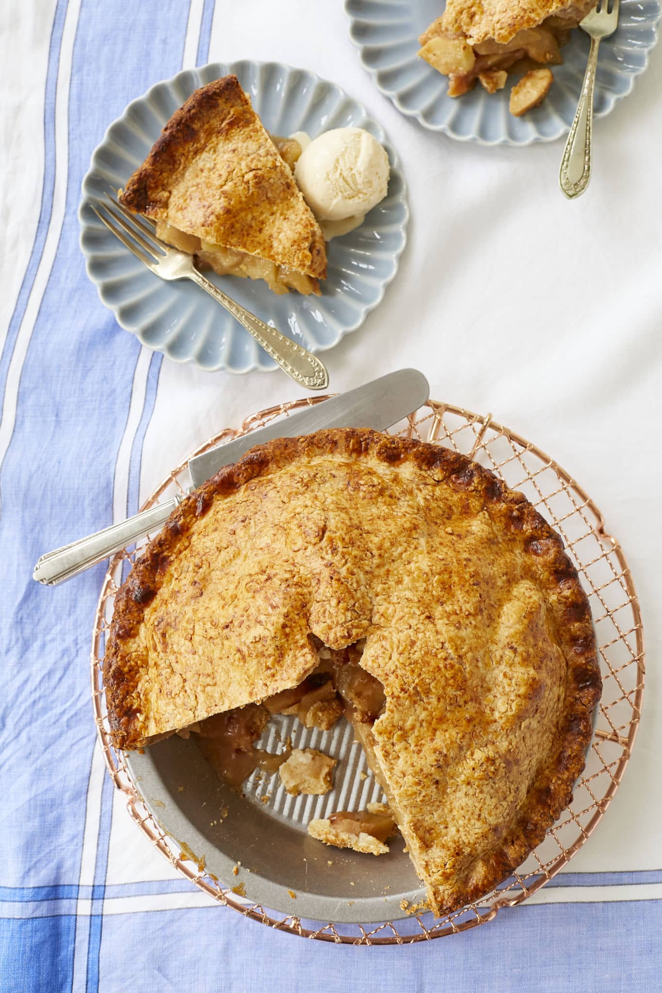 Homemade cheddar apple pie is served from the baking dish. Flecks of cheddar cheese can be seen in the crispy pie crust.