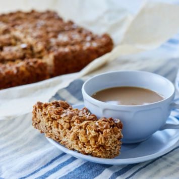 A serving of Traditional Irish Oat Flapjacks is served next to a cup of tea.