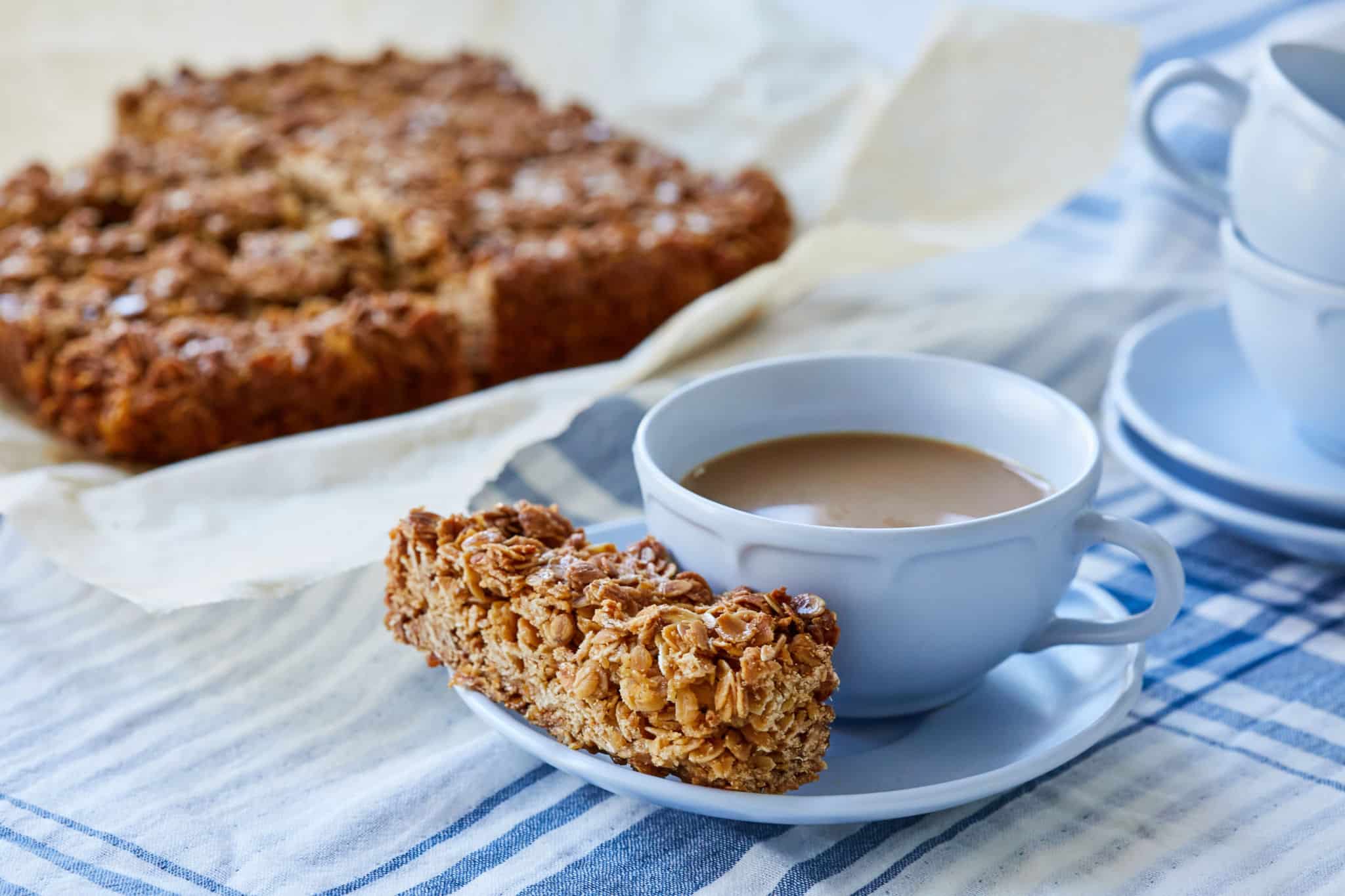 A serving of Traditional Irish Oat Flapjacks is served next to a cup of tea.