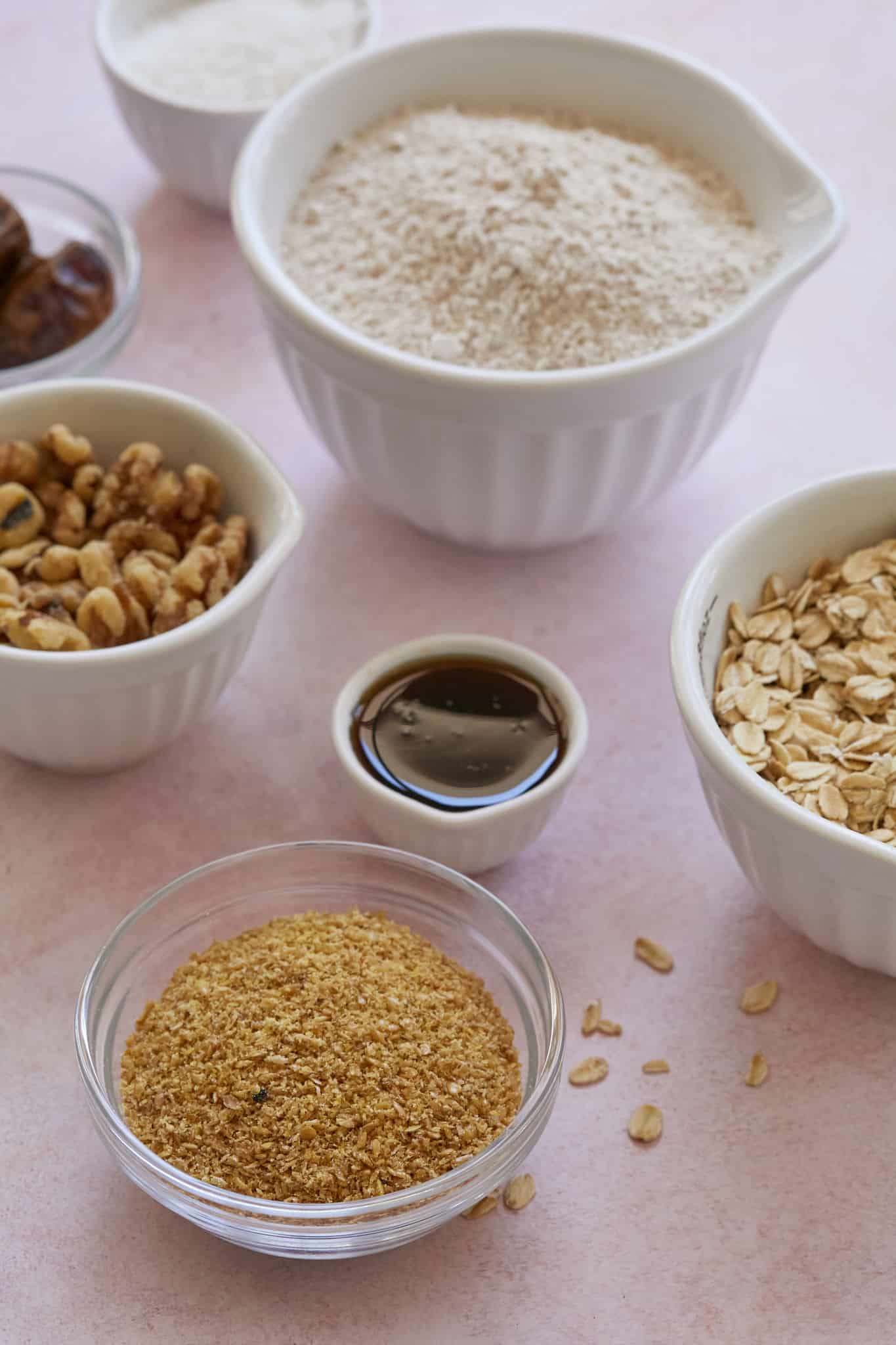 Healthy baking ingredients are displayed on a table, including maple syrup, nuts, oats, and dates.