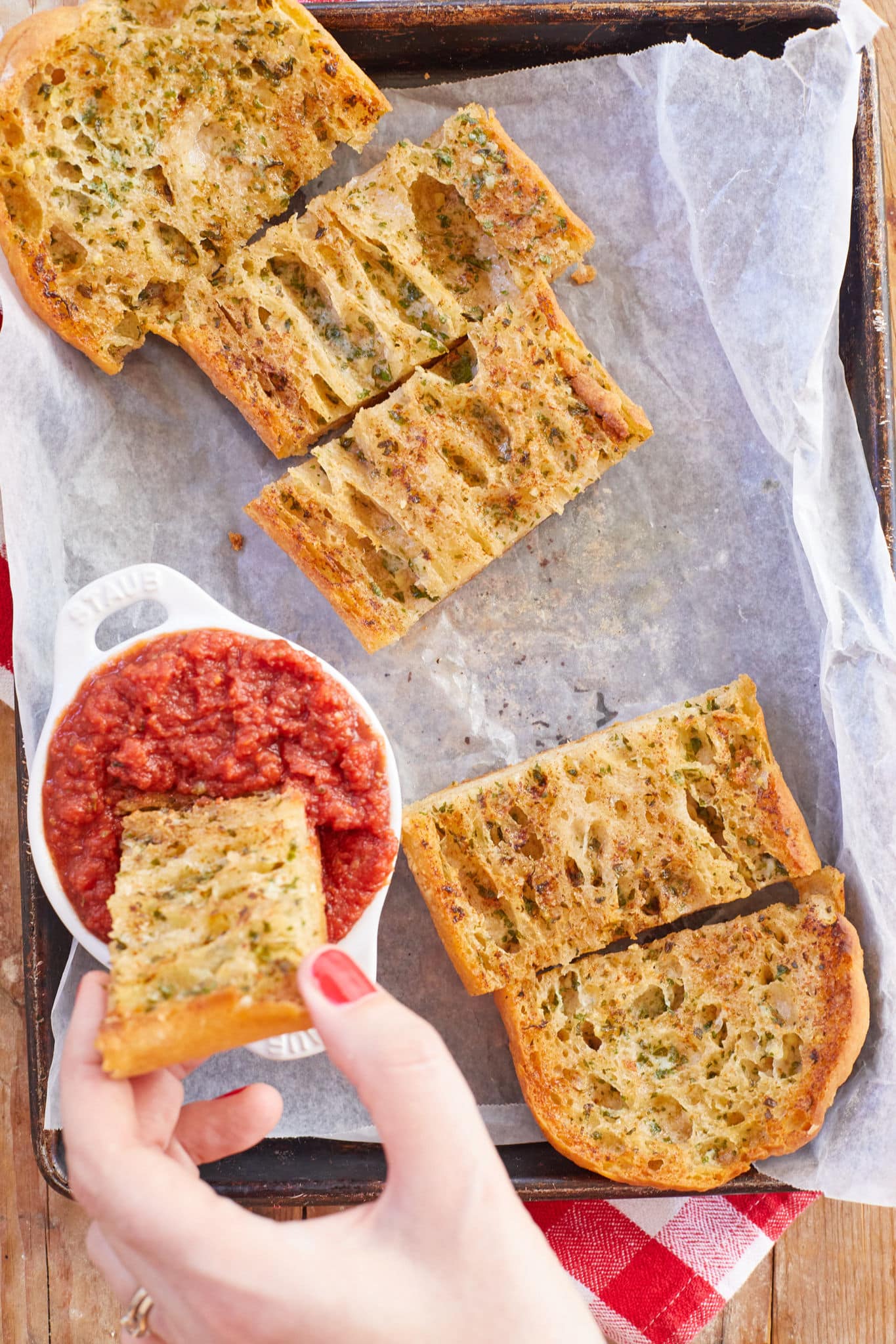 A piece of homemade garlic bread is dipped into homemade pizza sauce.