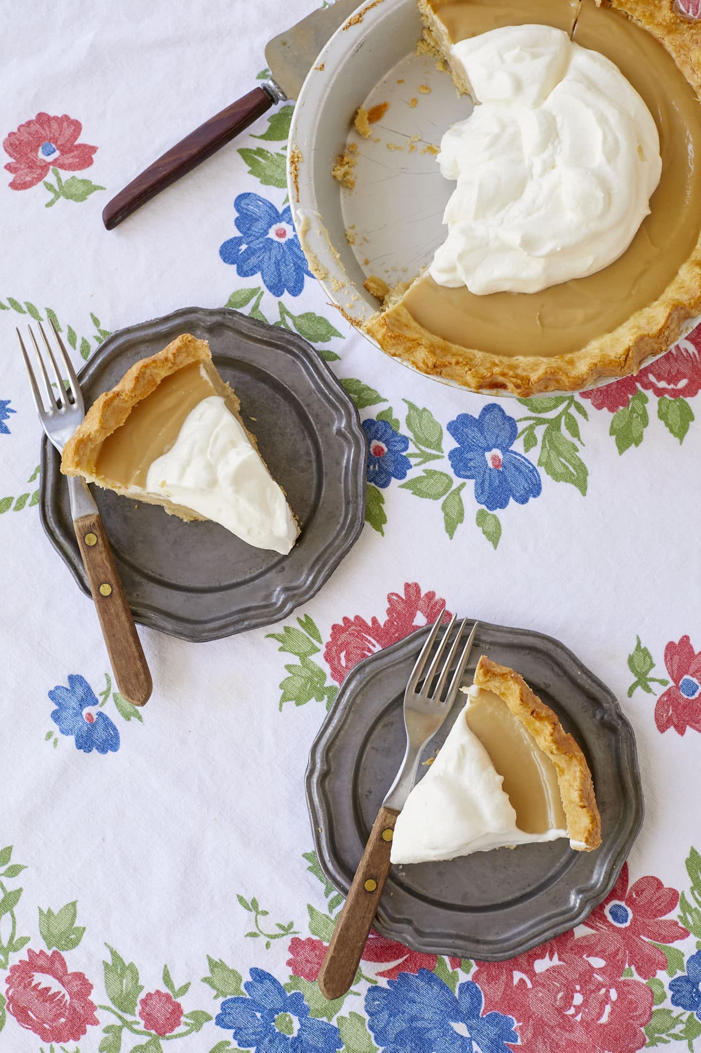 Two slices of creamy Maple Cream Pie are served on plates next to the pie tin.