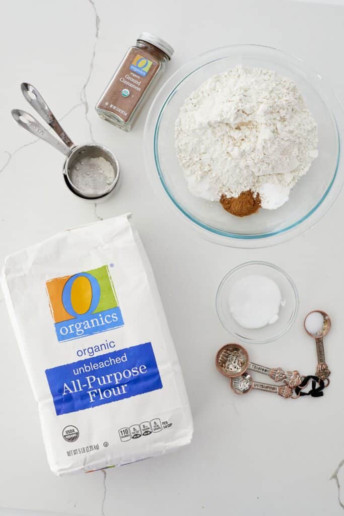 O Organics All Purpose flour is displayed in a clear bowl with O Organics Ground Cinnamon.