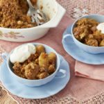 Homemade Pear Crumble is served in two blue bowls with fresh whipped cream.
