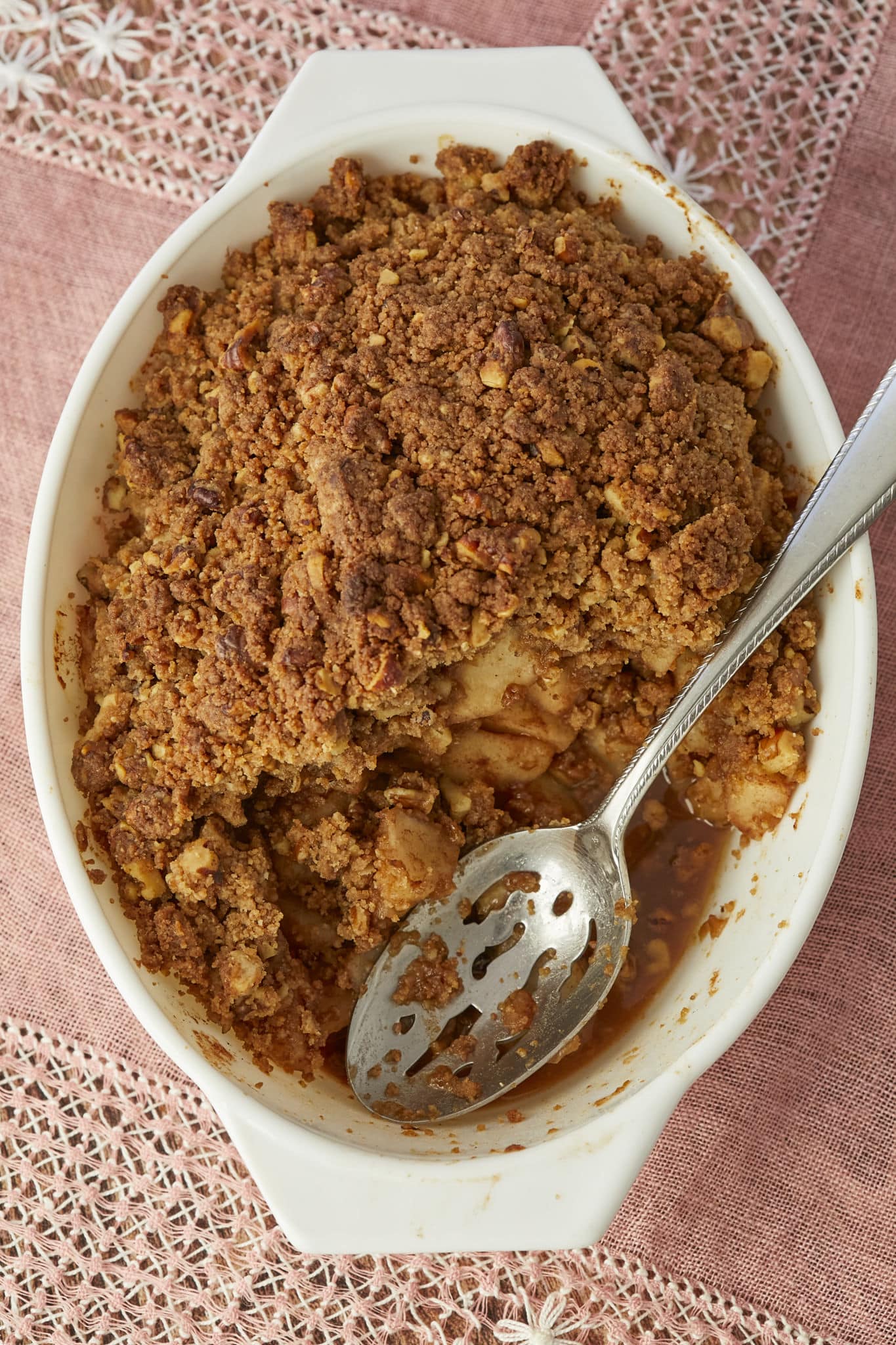 A metal spoon rests in a nearly half-eaten pear crumble