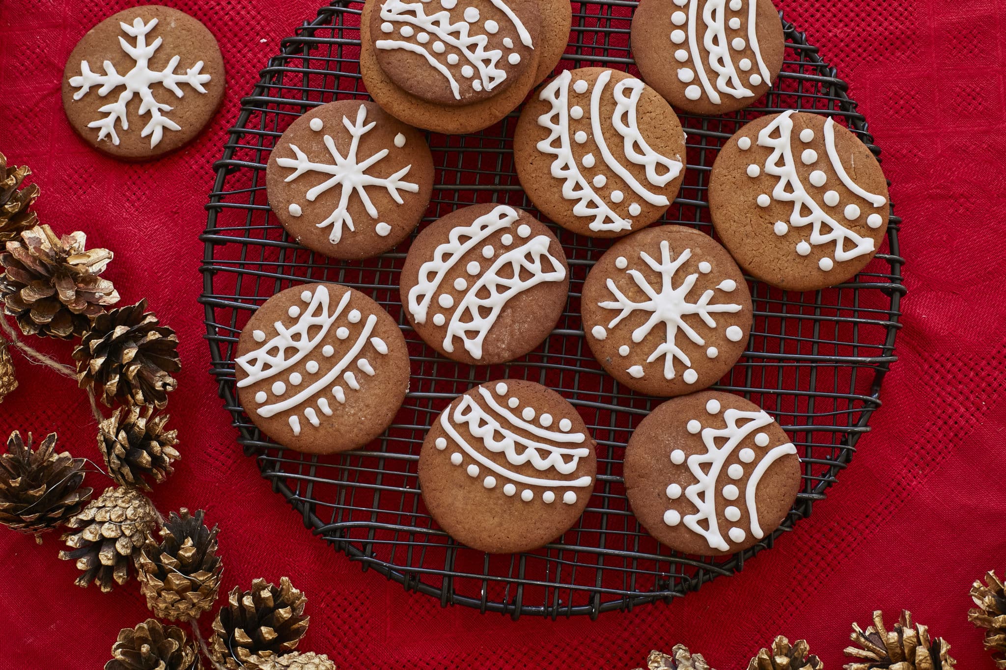 Homemade Pepparkakor, or Swedish Ginger Snaps, are presented on a black wire tray, decorated with festive Christmas icing, including snowflakes and ornaments.