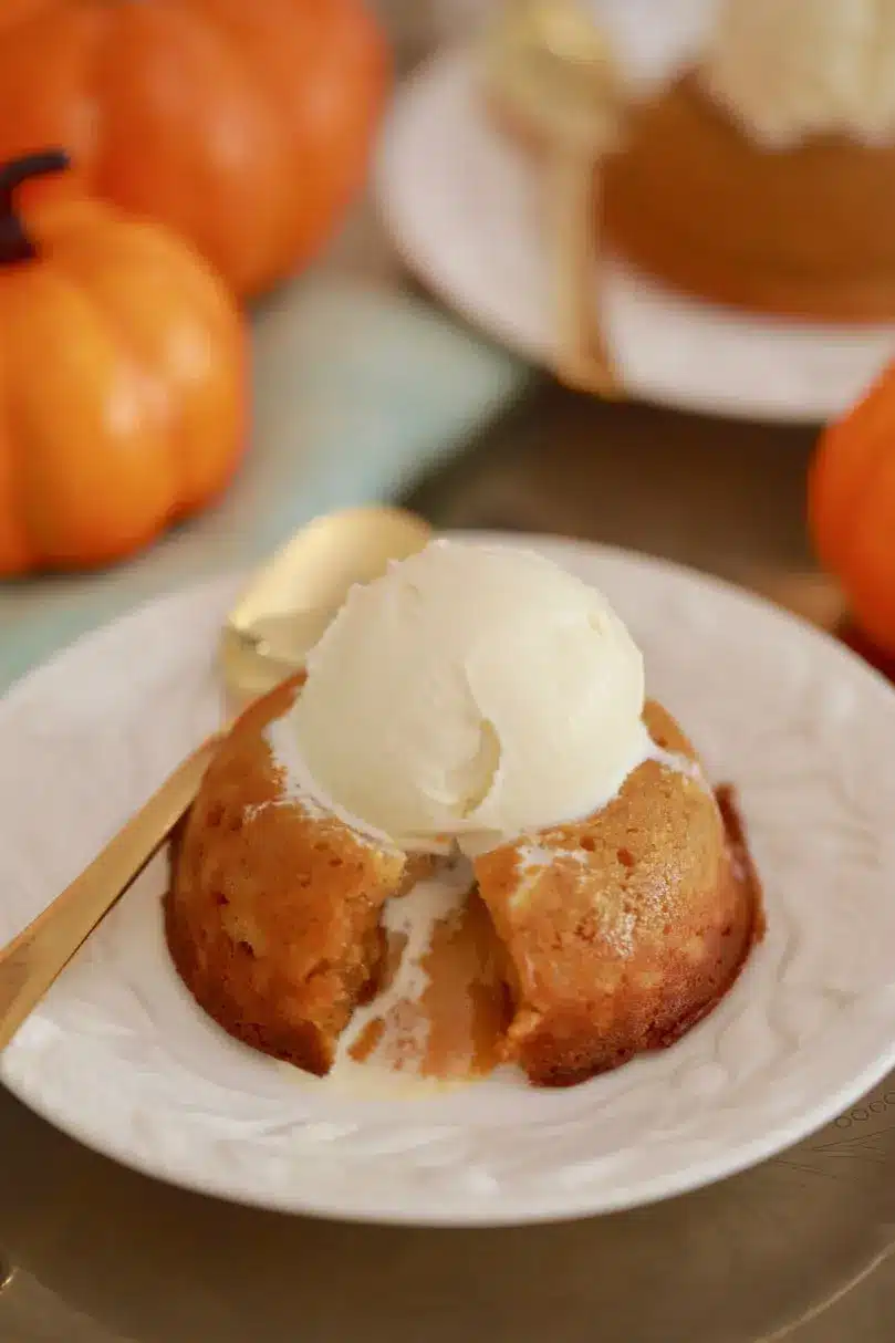 A white chocolate lava cake with pumpkin is served on a white dish with homemade vanilla ice cream.