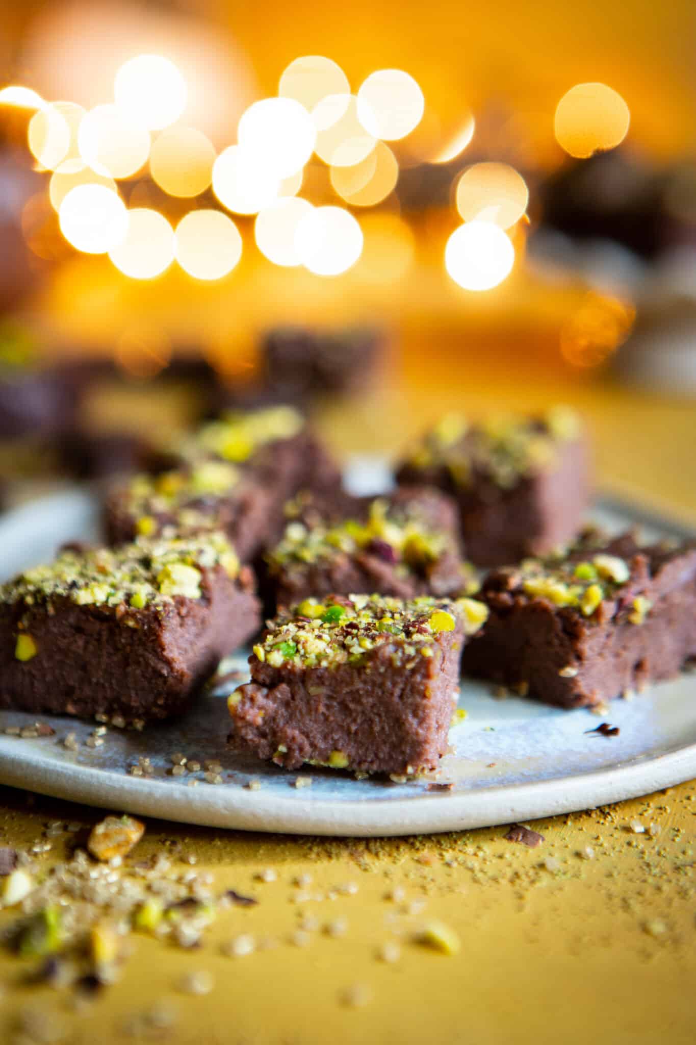 Bars of chocolate kalakand laid out on a blue plate, sprinkled with chopped pistachios. 