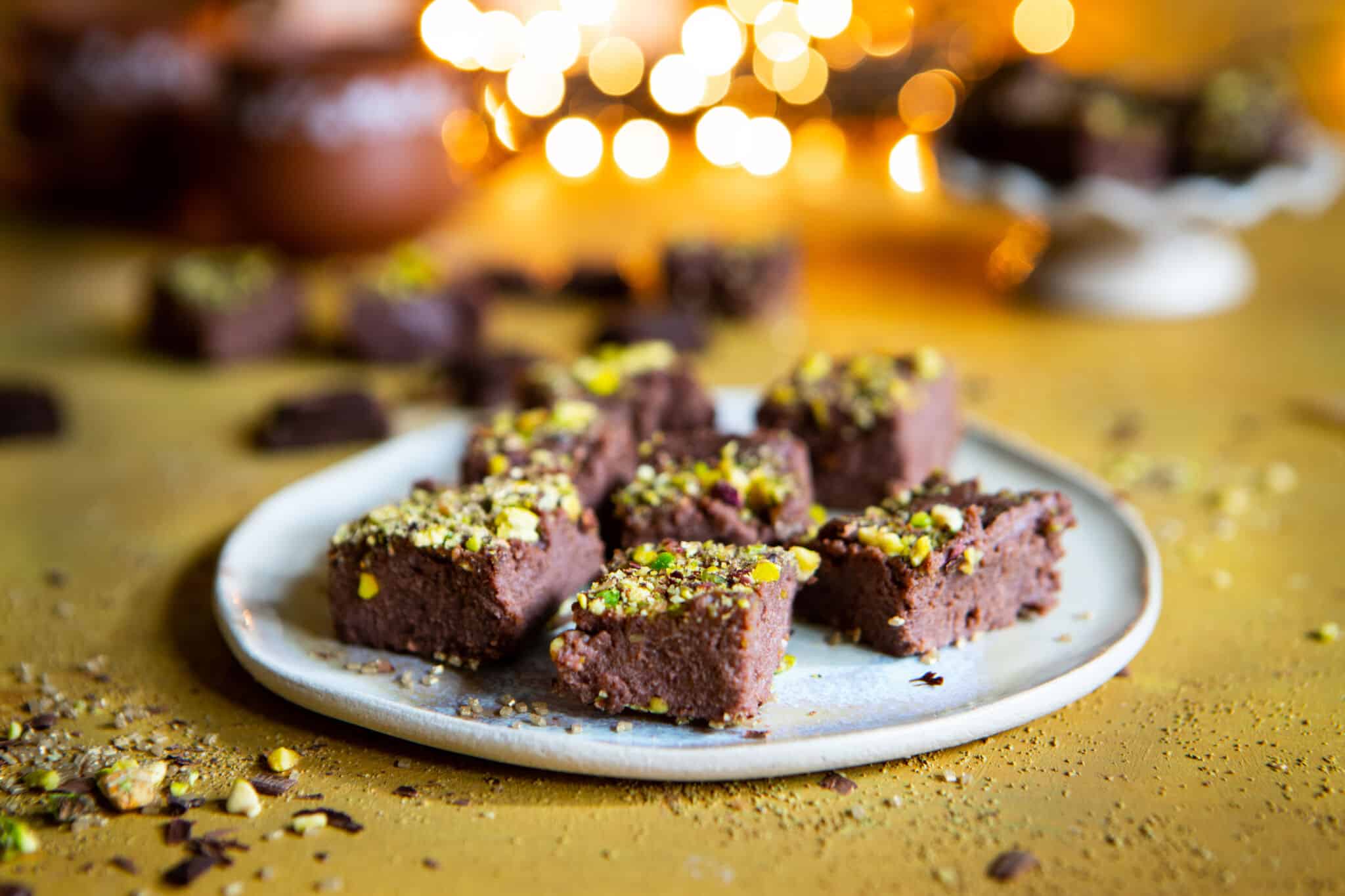 A plate of chocolate kalakand, cut into bars, sprinkled with chopped pistachios.