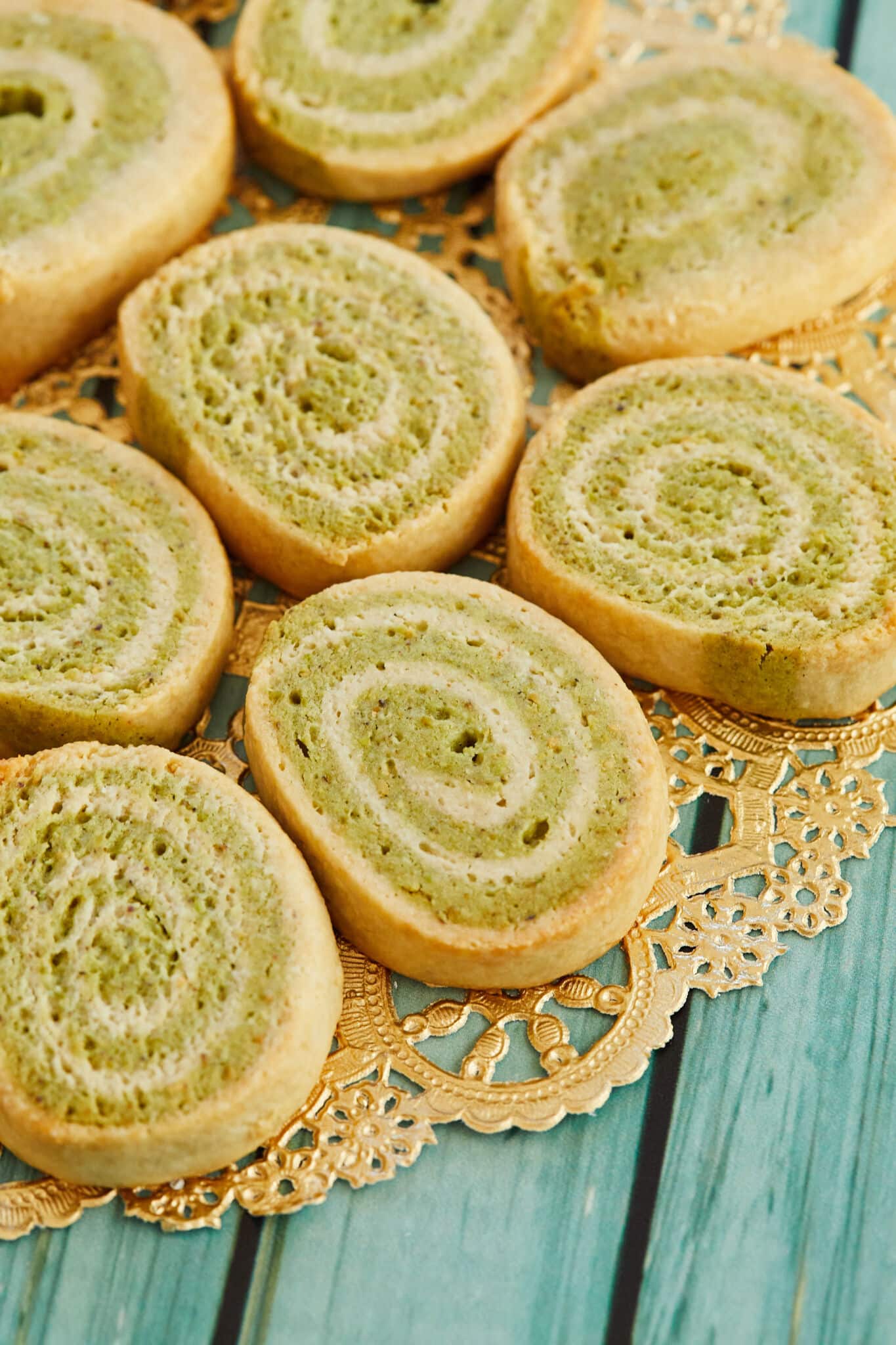 A display of kaju pista rolls sliced and laid out on a gold doily, on a wooden table.