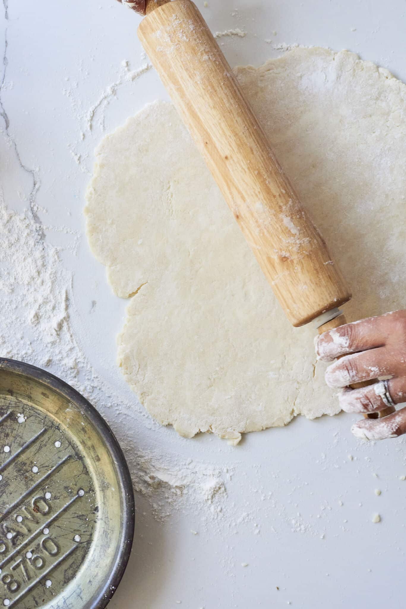 An image from overhead shows a rolling pin flattening pie crust to be placed into a pie pan off to the side.
