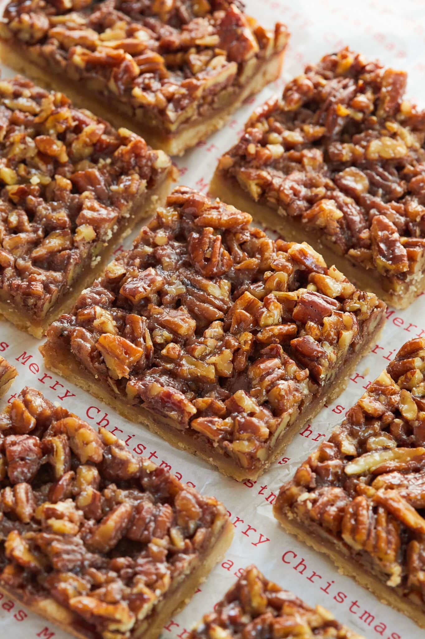 Maple pecan bars are cut into squares and served on top of parchment paper that reads, "Merry Christmas." 