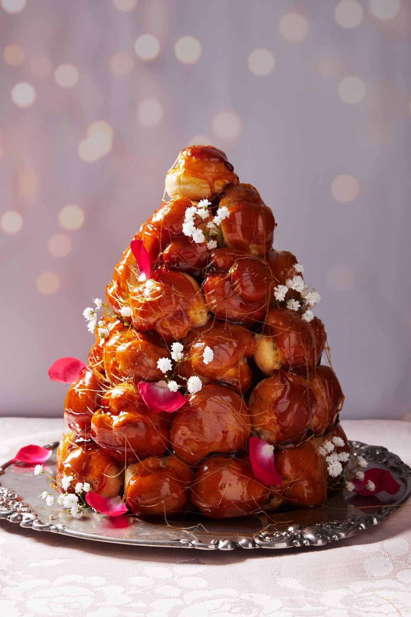 A Croquembouche Tower of profiteroles on a silver tray. Drizzled with caramel. 