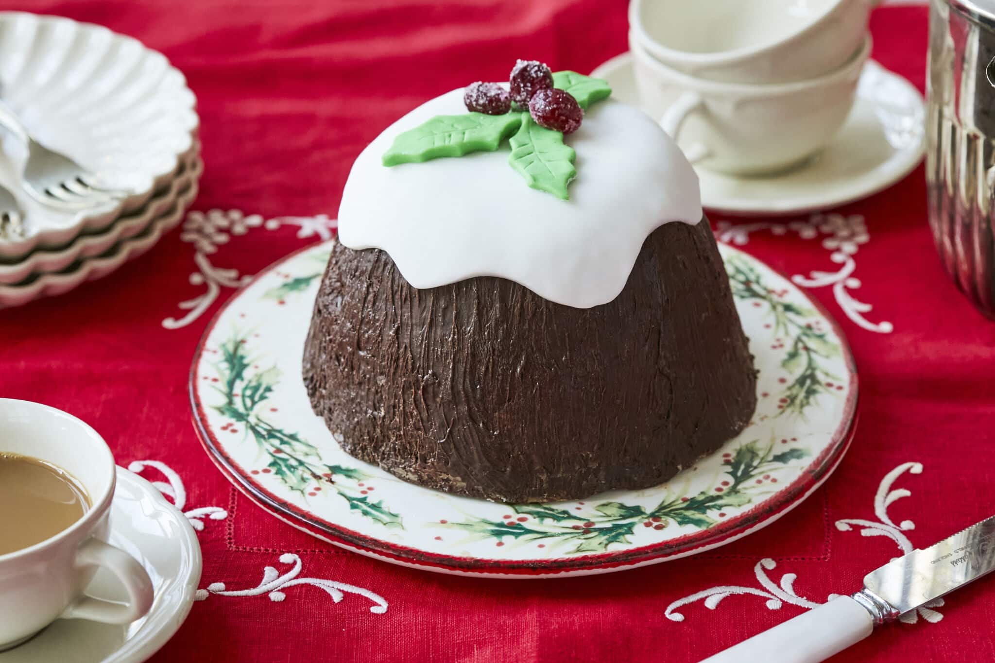 No-Bake Christmas Cake frosted with fondant holly garnish, on a Christmas plate.