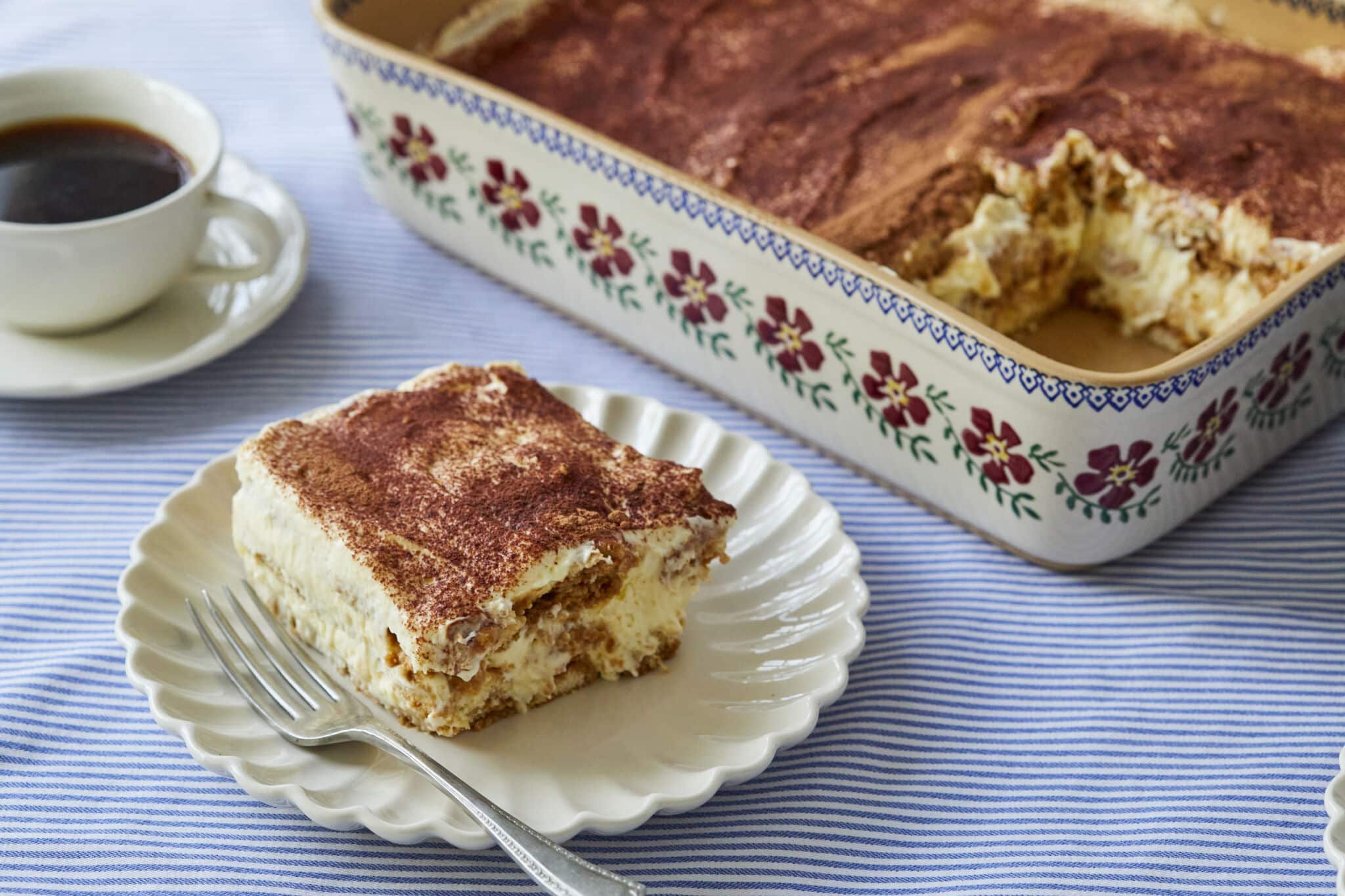 Single serving of the best Tiramisu recipe and a full serving tray of more to be served along with a cup of coffee