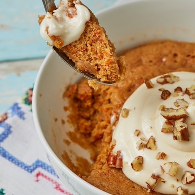 Soft, moist carrot cake cooked in a bowl in the microwave. It's loaded with nuts, raisins and topped with creamcheese frosting.