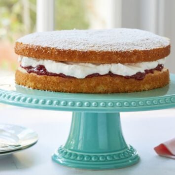 Victoria Sponge Cake made with light and airy sponge cake and filled with soft whipped cream and sweet strawberry jam topped with powdered sugar.