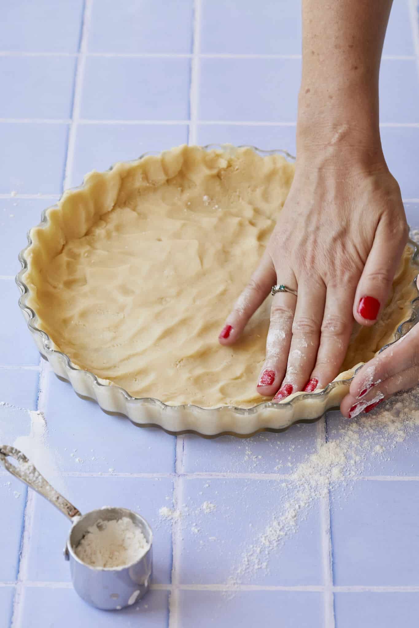 Using fingers to press Pâte Sucrée pastry into a tart dish. Pâte Sucrée can also be rolled out if chilled. 