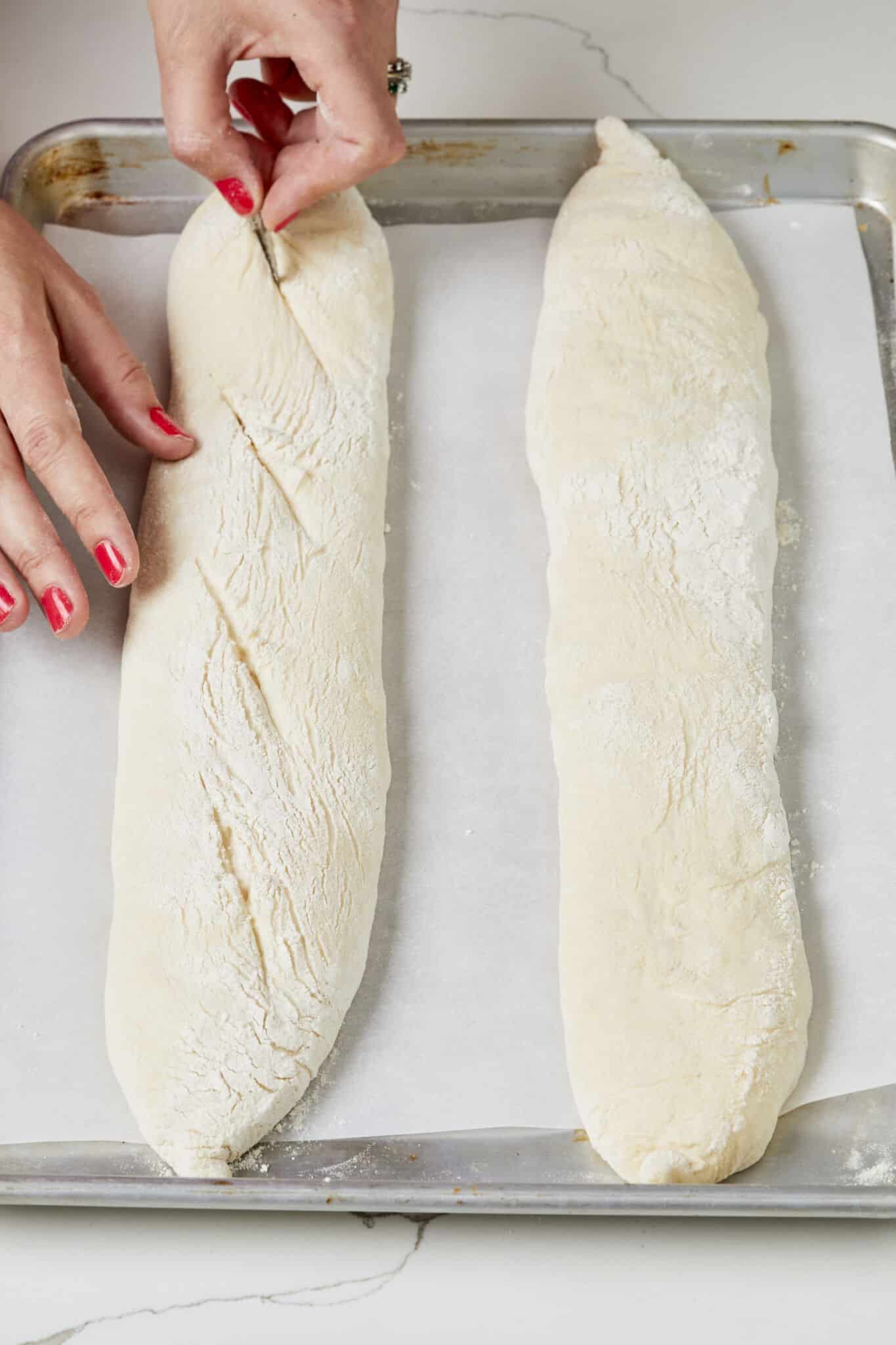 Scoring baguettes with a sharp blade before baking. 