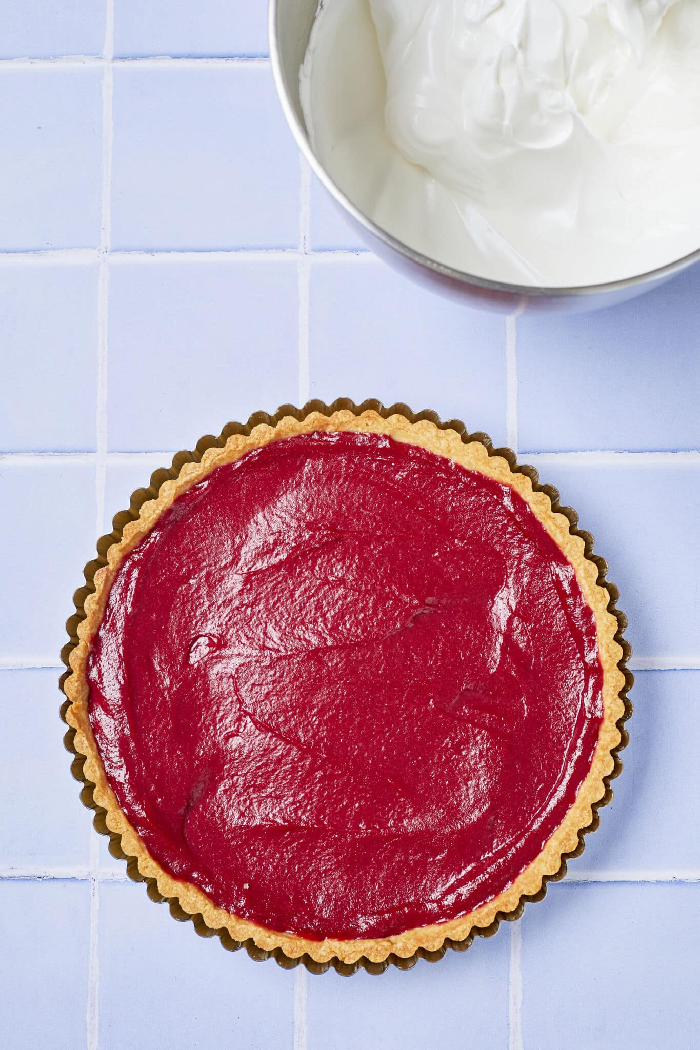 Step-by-step instruction: fill the baked curst with raspberry curd and bake again to bind them together better. A bowl of topping is ready on the side. 