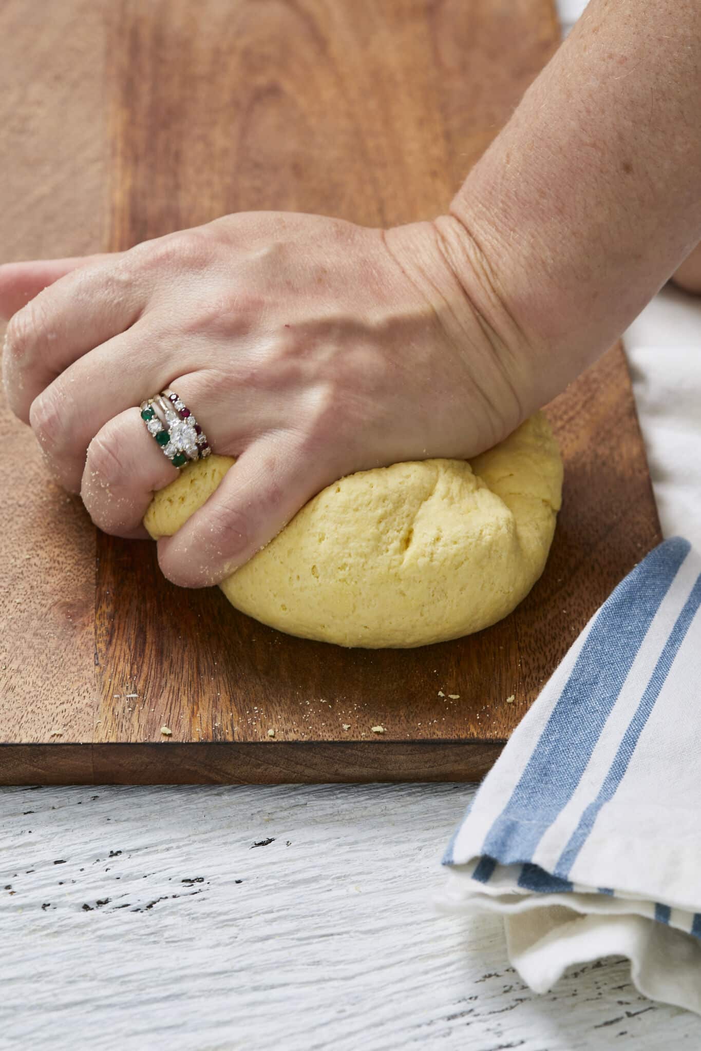 Kneading semolina pasta dough on a wooden surface. 