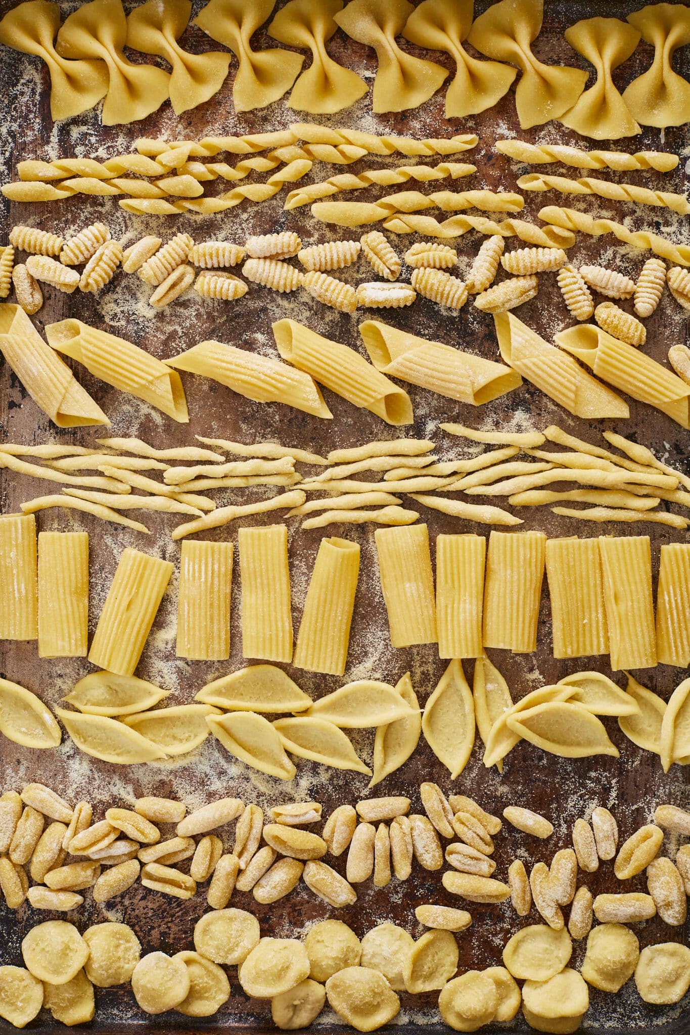 The authentic 2-Ingredient Semolina Pasta is in gorgeous yellow color and made into nine different shapes and sizes. From top to bottom are: Farfalle, Busiate, gnocchi, penne,Trofie, Rigatoni, Foglie, Malloreddus, Orecchiette Pasta. Very versatile in holding sauces. 
