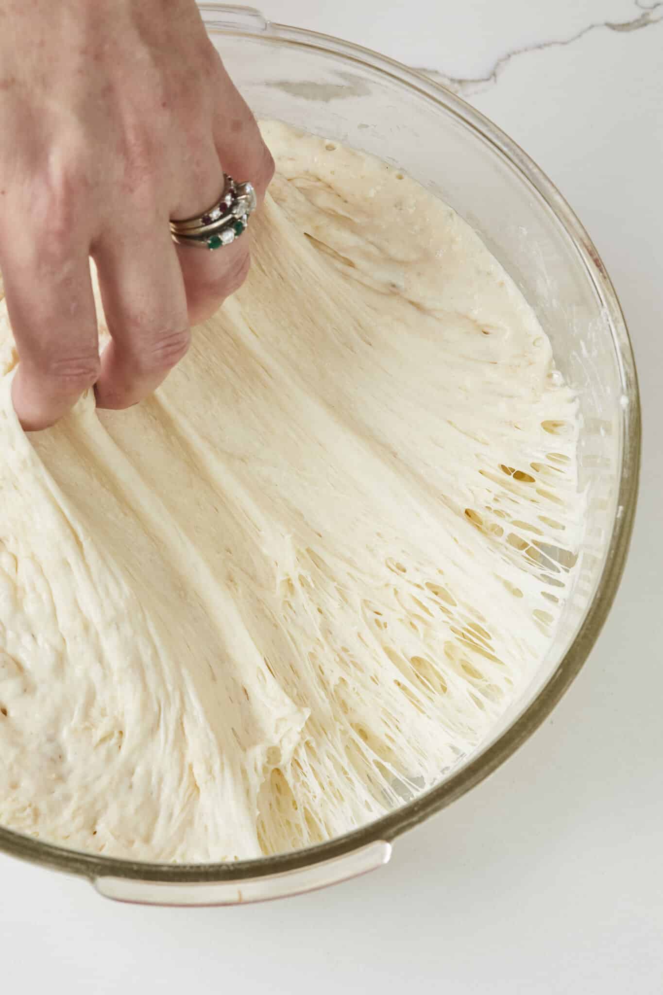 Step-by step instructions on how to make the No Knead Sandwich Bread: after the bulk fermentation the dough has developed loads of gluten strands and air pockets. Knocking out the air will strengthen the dough.
