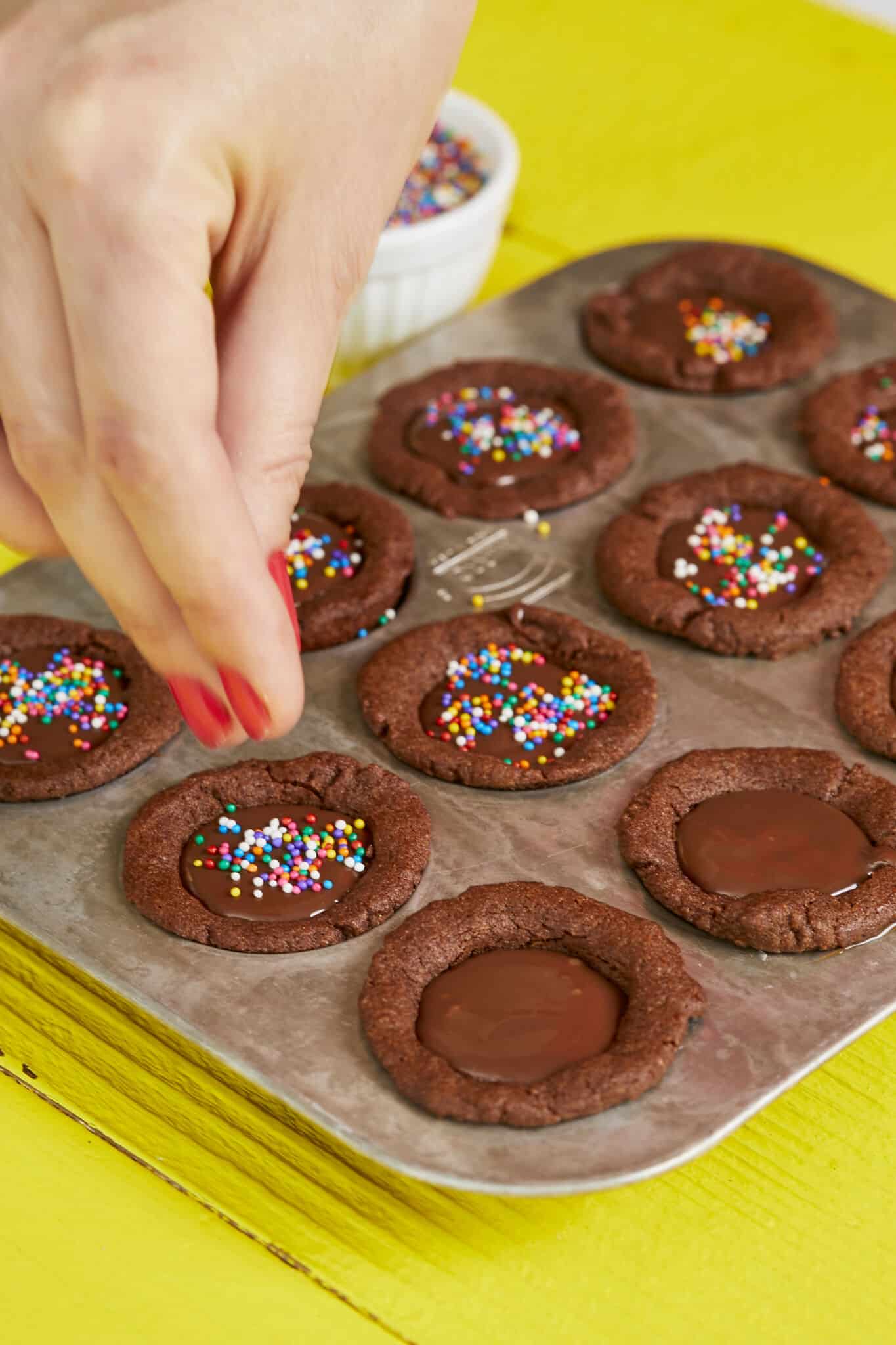 Chocolate Cookie Cups are baked and set perfectly in a 12-well mini cupcake pan. These bite-size cups have lightly crispy edges, soft and chewy inside with a silky ganache filling. They're decorated with colorful sprinkles.