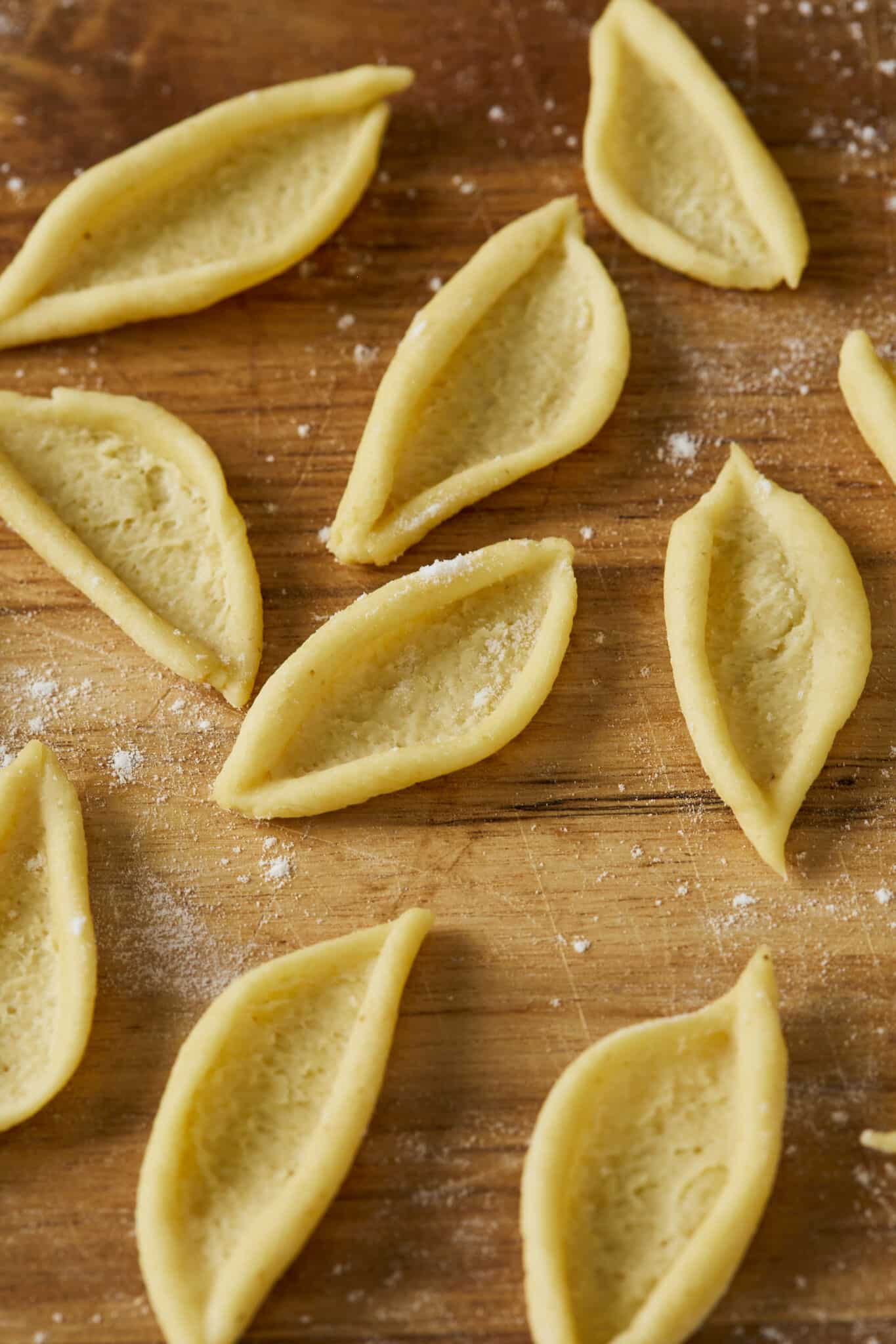 Olive Leaf Pasta is drying on a lightly-floured wood board. Its versatile flat, curved shape seems perfect for capturing every bite of your favorite sauce. 