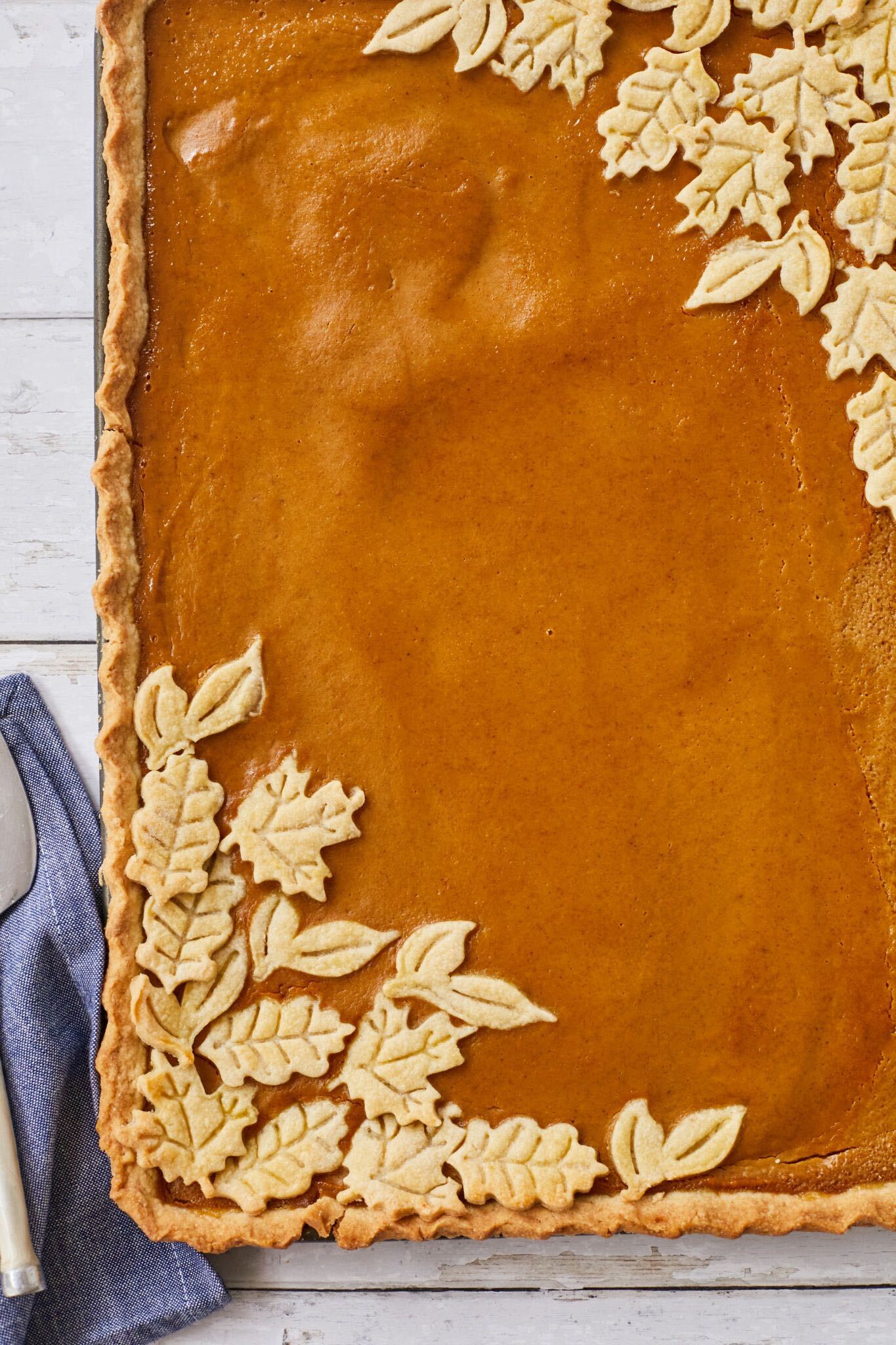The Incredible Pumpkin Slab Pie is baked to perfection with golden crust, beautifully cut-out pastry leaves, and silky smooth filling in golden orange color. 