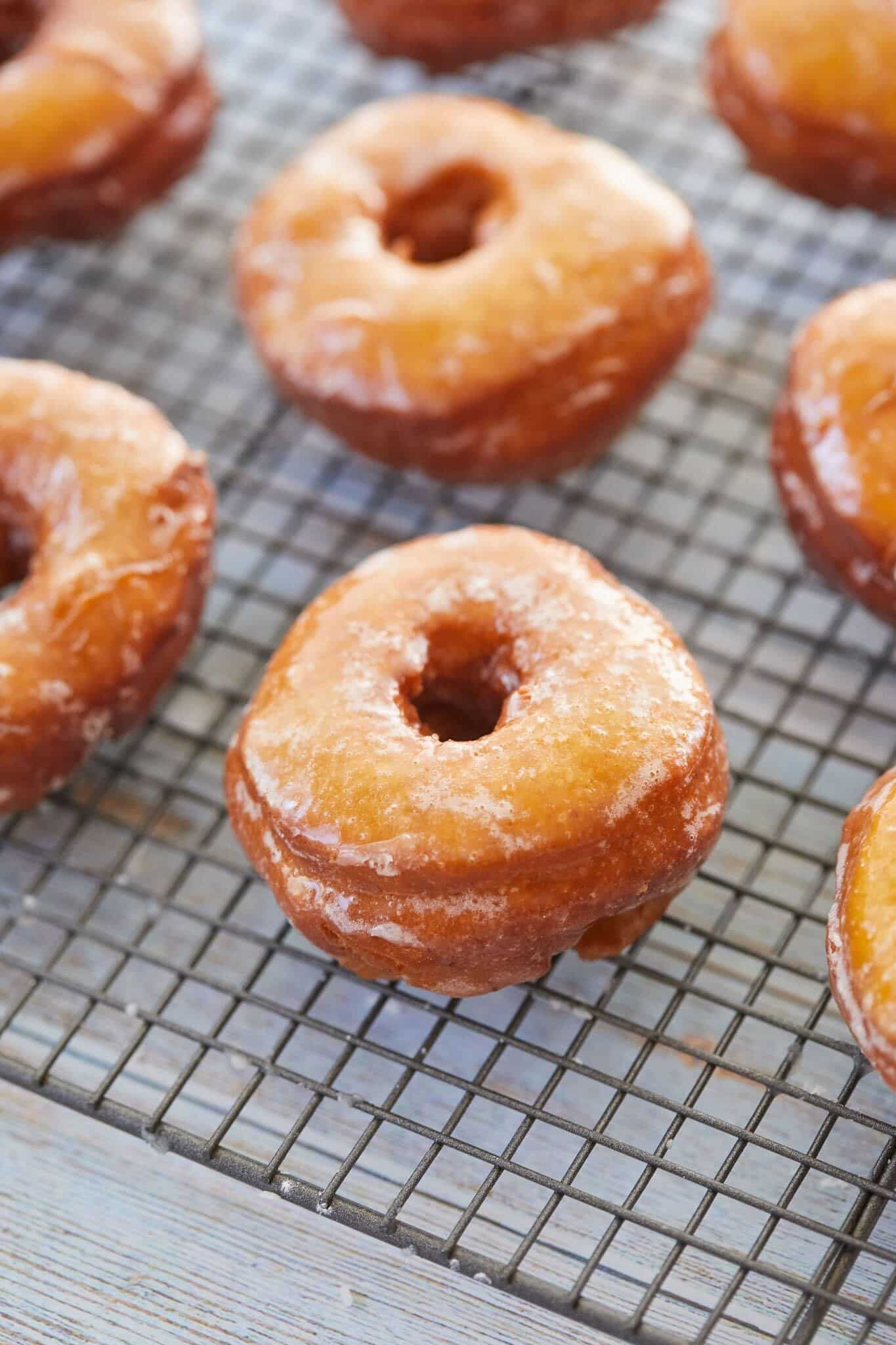 Homemade Glazed Pumpkin Donuts are baked to a perfect golden orange color and cooling on a wire rack. They're soft and moist, covered with glossy sweet glaze. 