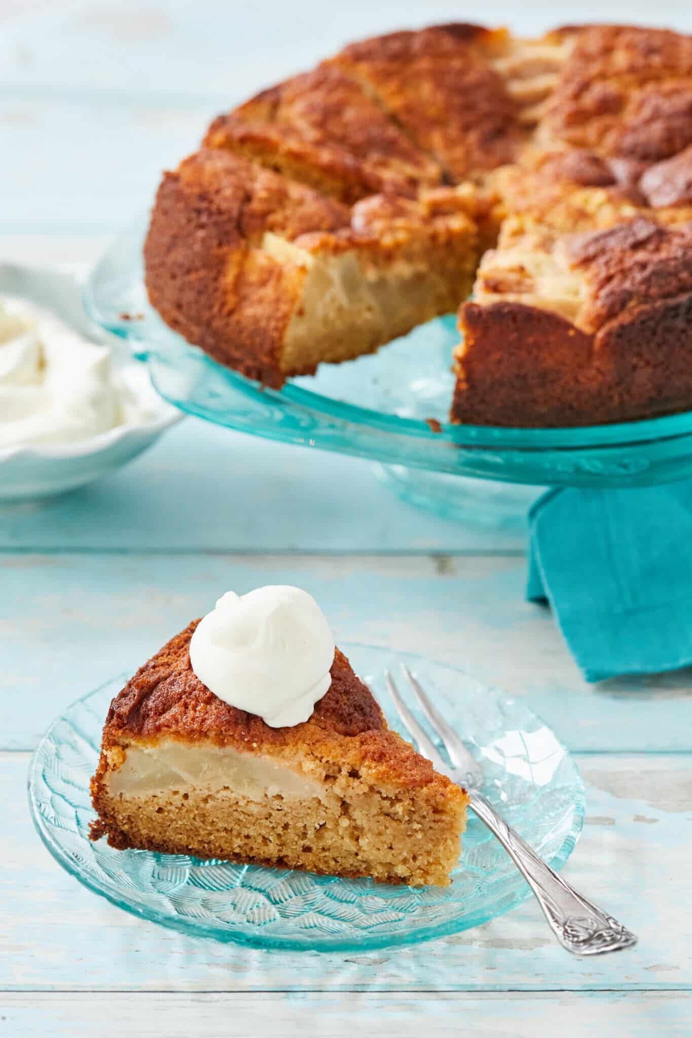 The gorgeous Warm Pear and Honey Cake is served on a big glass cake stand with one slice on a small dessert plate. The moist cake has a beautiful golden brown color, loaded with soft and juicy pears, topped with a big scoop of vanilla ice cream. 