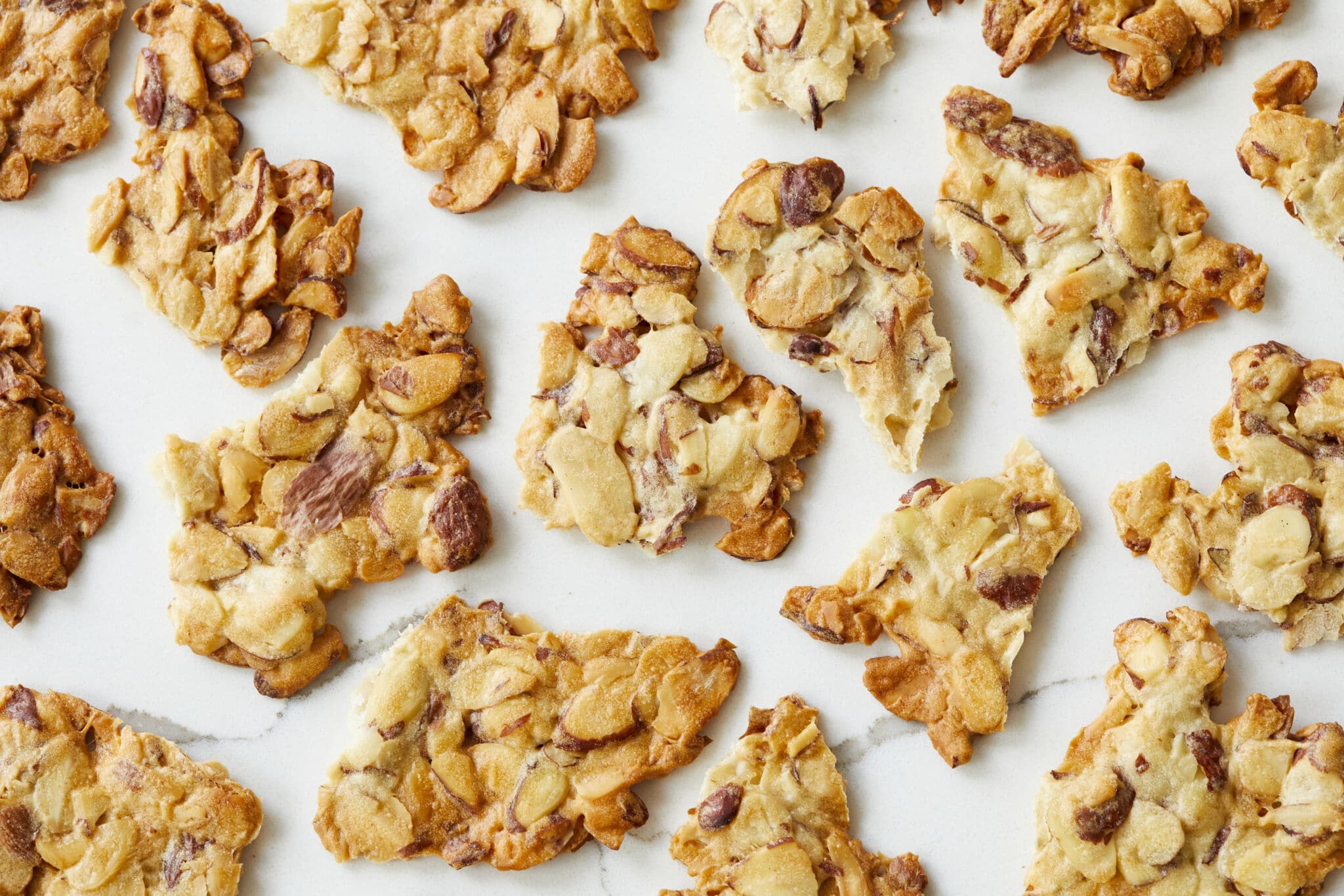 An overhead shot at satisfying Almond Crisps shows clusters of thin slivered almonds that are baked until crunchy and caramelized golden brown.
