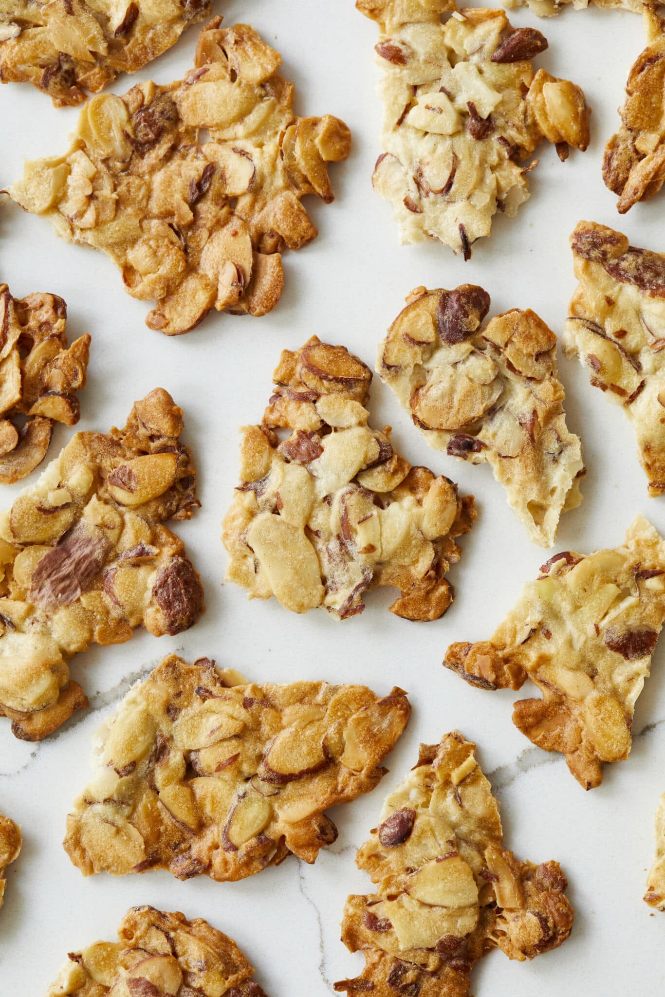 An overhead shot at satisfying Almond Crisps shows clusters of thin slivered almonds that are baked until crunchy and caramelized golden brown. 