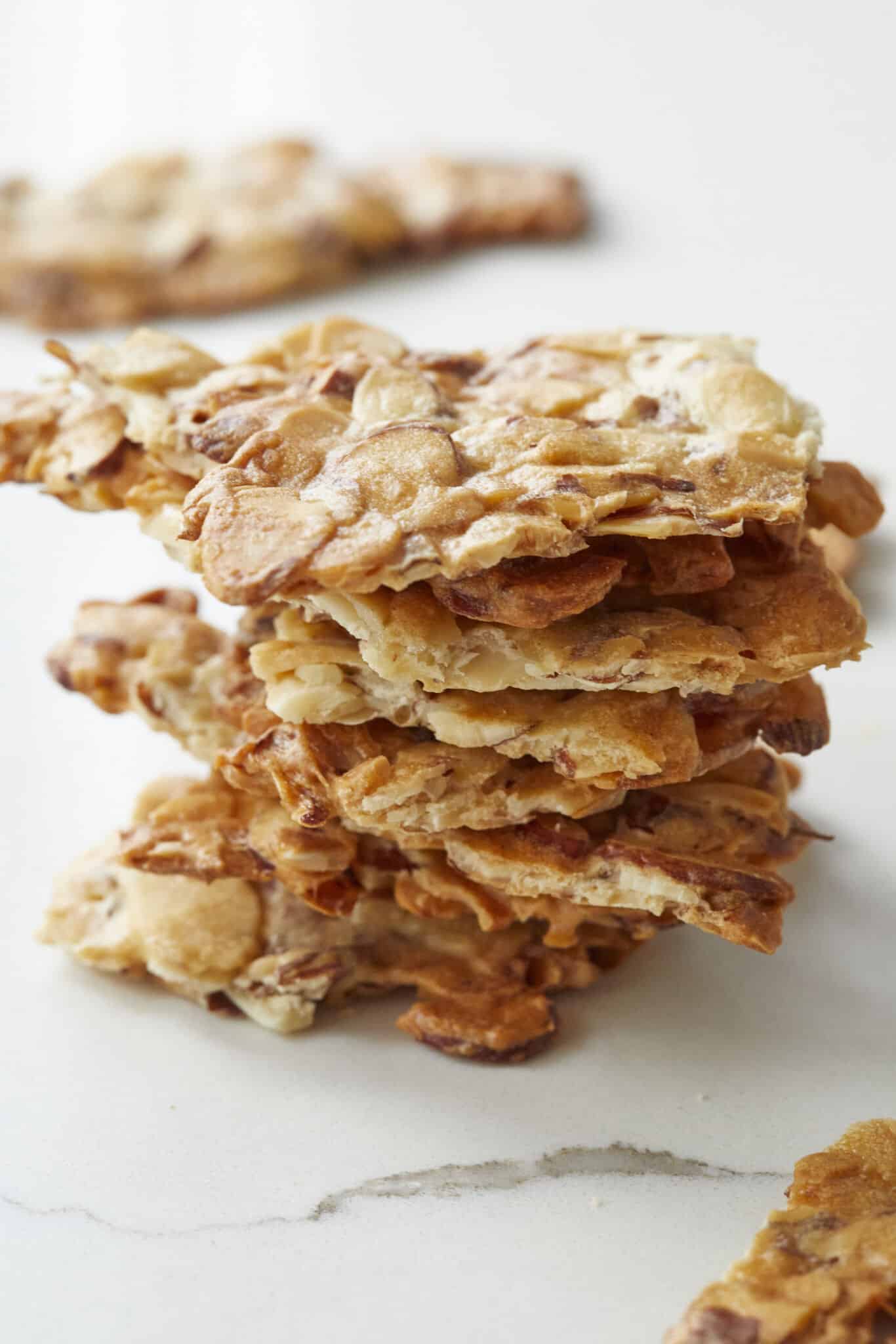 A close shot at a stack of satisfying Almond Crisps shows thin slivered almonds that are baked until crunchy and caramelized golden brown. 