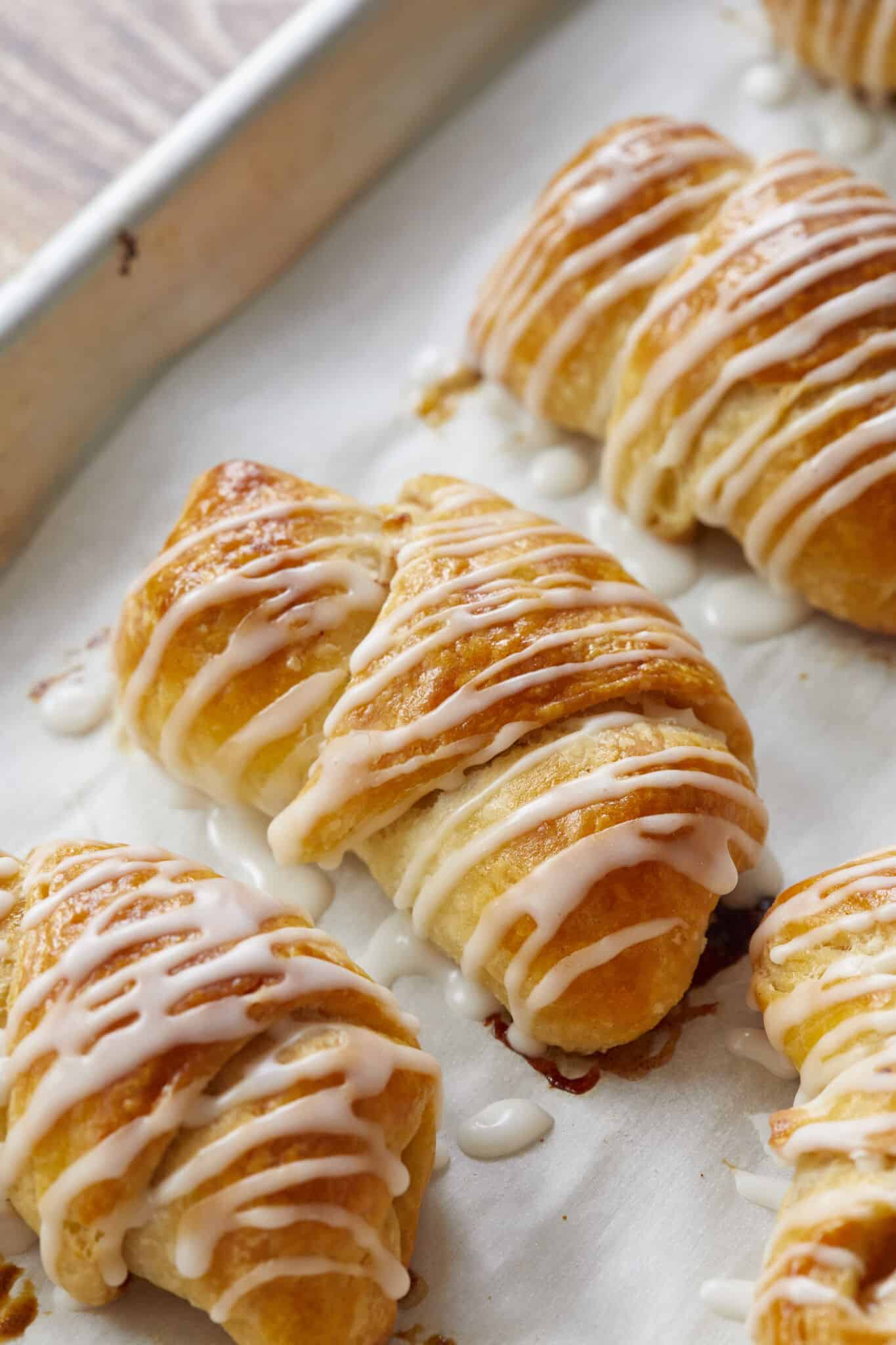 The rolls are baked until deep golden brown in a parchment-lined baking sheet. Vanilla glaze is drizzled over crescent rolls and setting for about 30 minutes. 