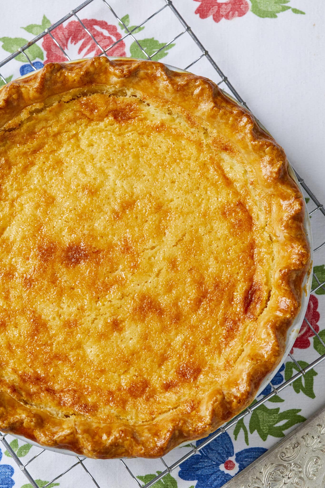 A close shot at the most part of an Irresistible Buttermilk Pie which is baked perfect with golden-brown crust and creamy, tangy filling. It's cooling on a wire rack. 