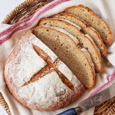 Joululimppu (Finnish Christmas Bread) is a spiced, subtly sweet rye bread and is baked in a round shape scored cross on top. It's dusted with flour and sliced in a basket lined with a kitchen towel.
