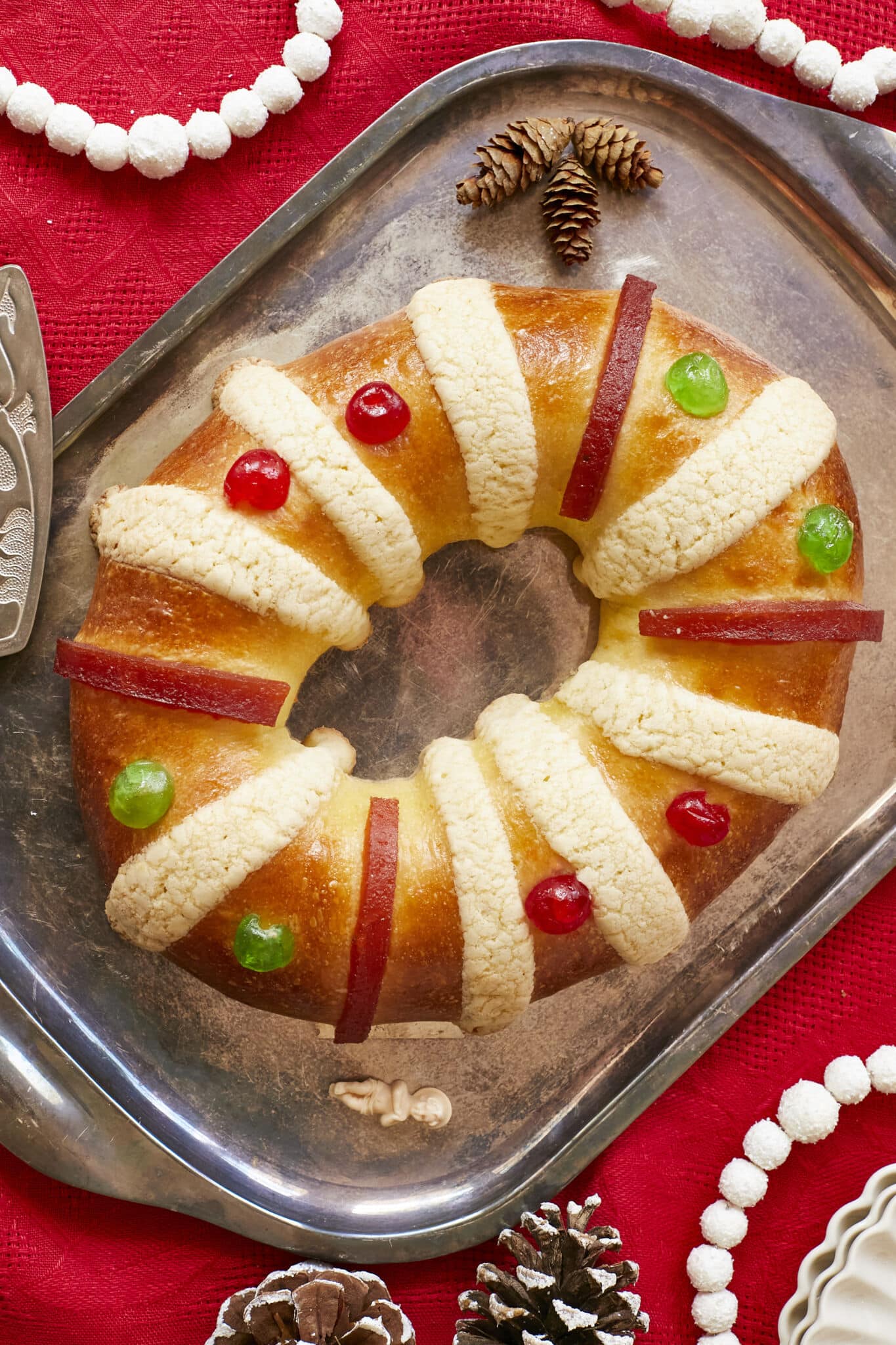 Rosca de Reyes (Three Kings Bread)is baked until golden brown. It's infused with orange zest and decorated with festive candied cherries, strips of quince paste, and sugar paste.