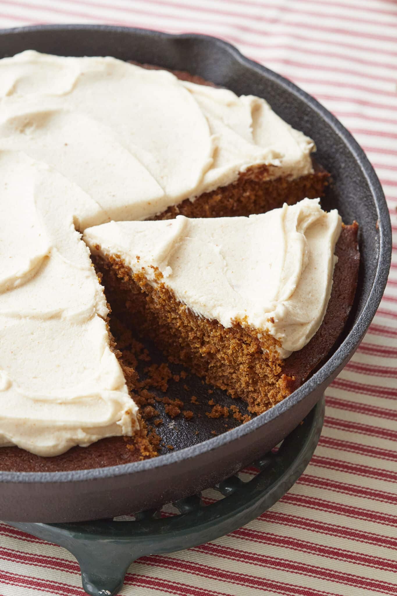 A big slice of rich, moist Gingerbread Cake is cut in the cast iron skillet, crowned with velvety Brown Butter Frosting. 