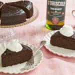 Rich, moist and decadent Irish whiskey Chocolate Cake are sliced and served with whipped cream. A bottle of whiskey and extra whipped cream are on the side.