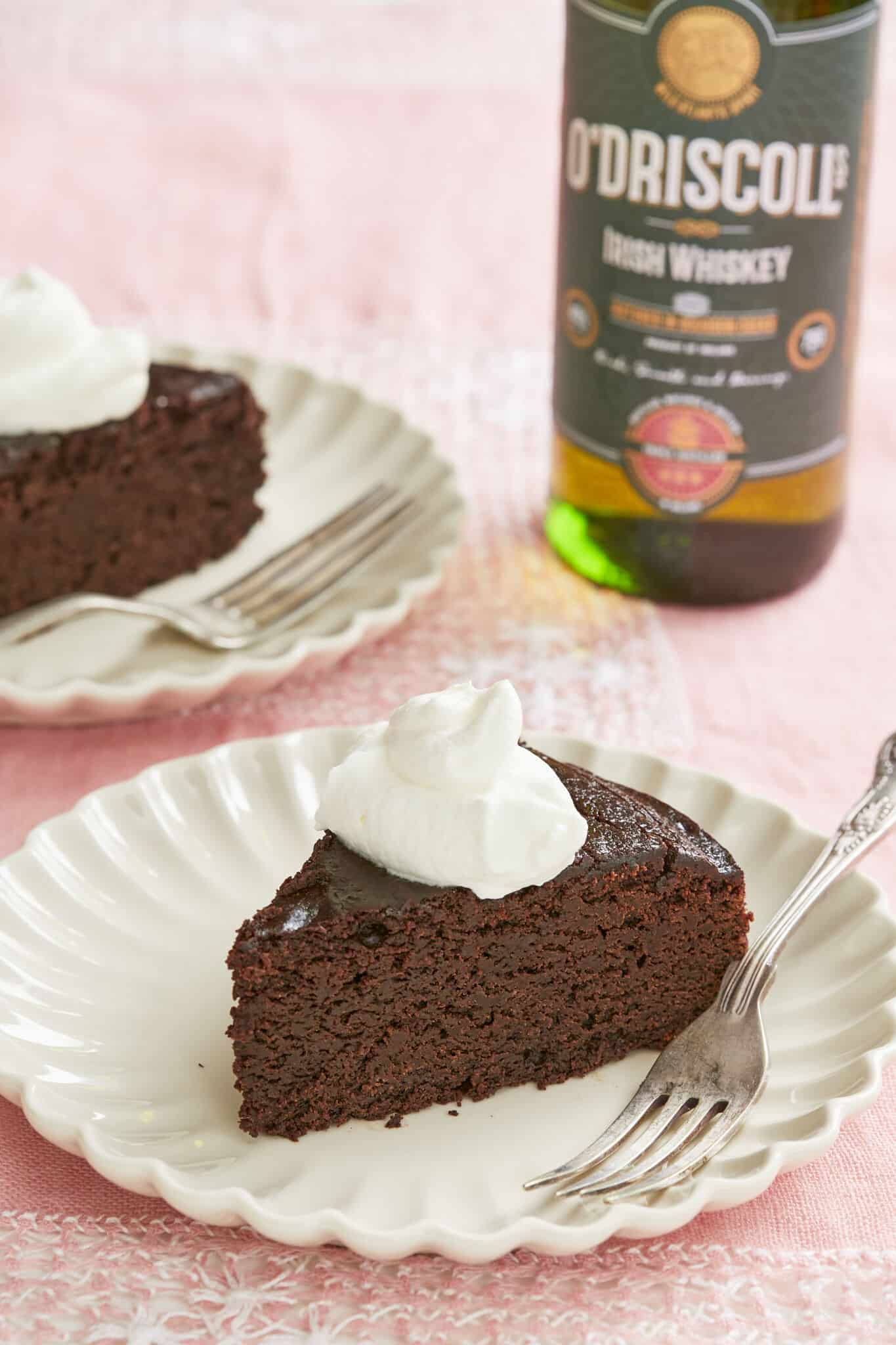 Rich, moist and decadent Irish whiskey Chocolate Cake are sliced and served with whipped cream. A bottle of O'Driscolls Irish Whiskey is served on the side.