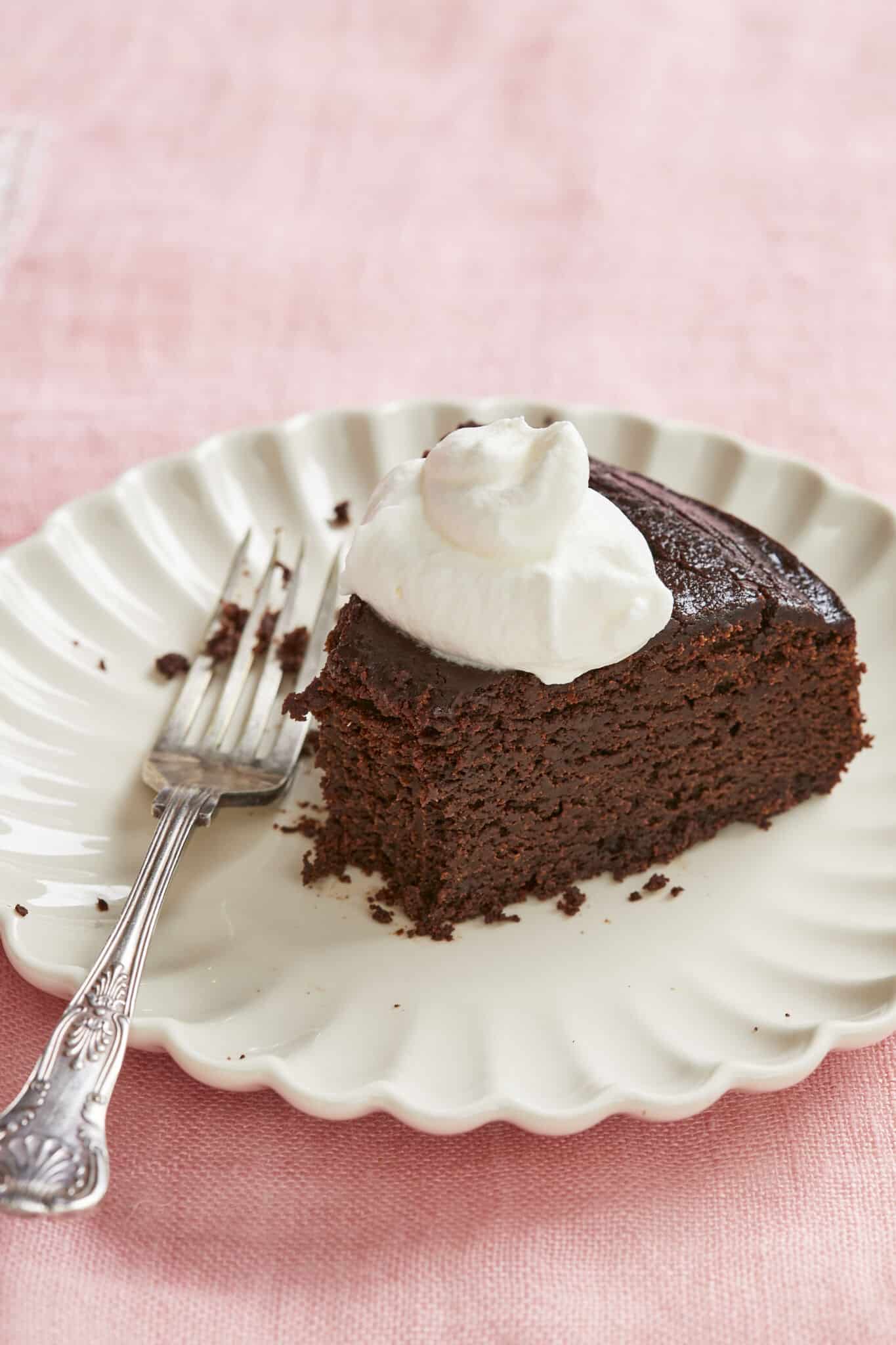 A close-up shot at the decadent Irish whiskey Chocolate Cake slice shows its rich, moist and smooth inside. It is served with whipped cream. 