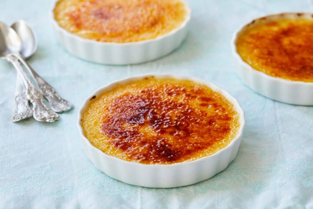 Three dishes of Passionfruit Crème Brûlée is served. Each Passionfruit Crème Brûlée has a rich custard base topped with a layer of amber-color caramelized sugar.